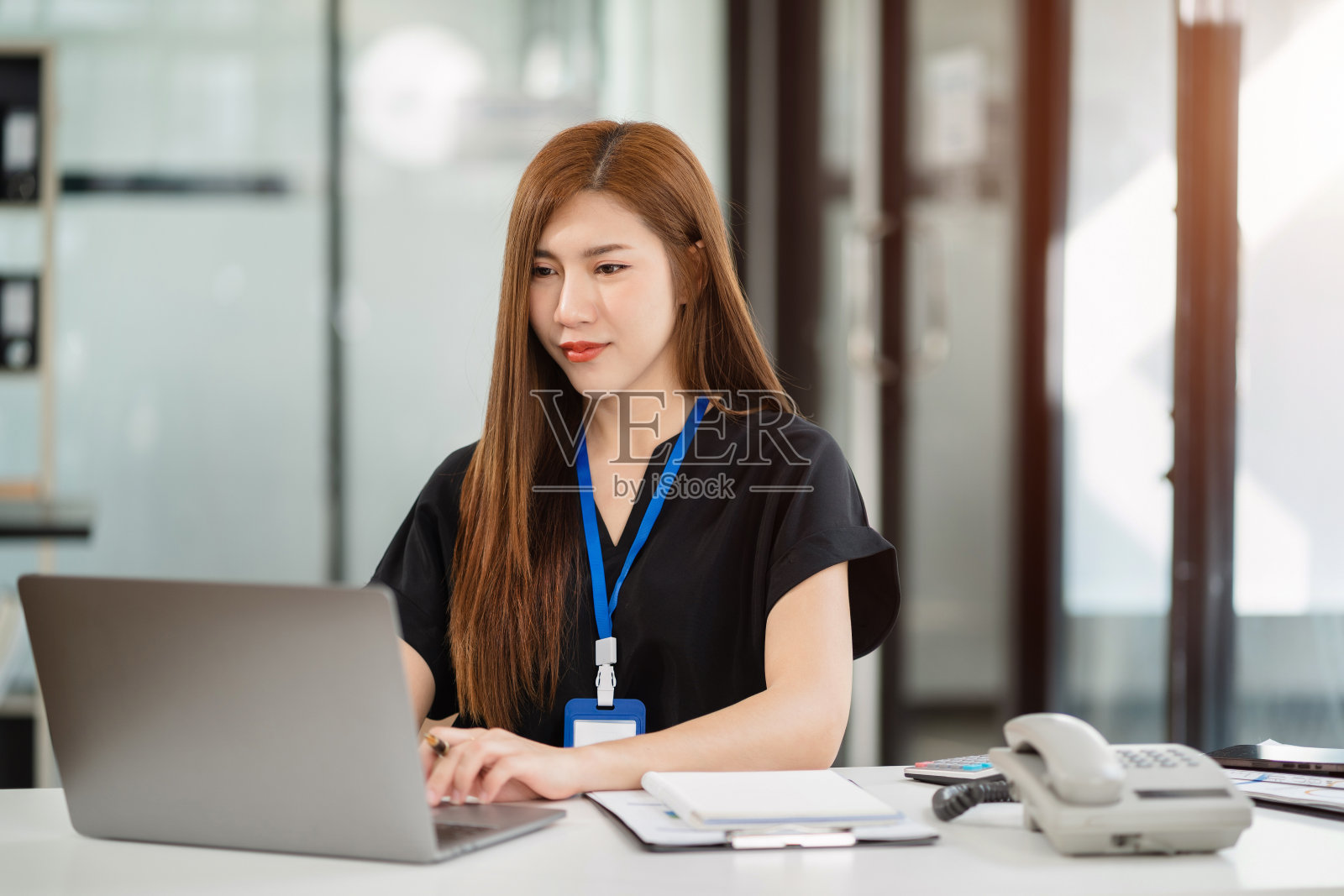 女性在早上使用智能手机和笔记本电脑在办公桌前工作。照片摄影图片
