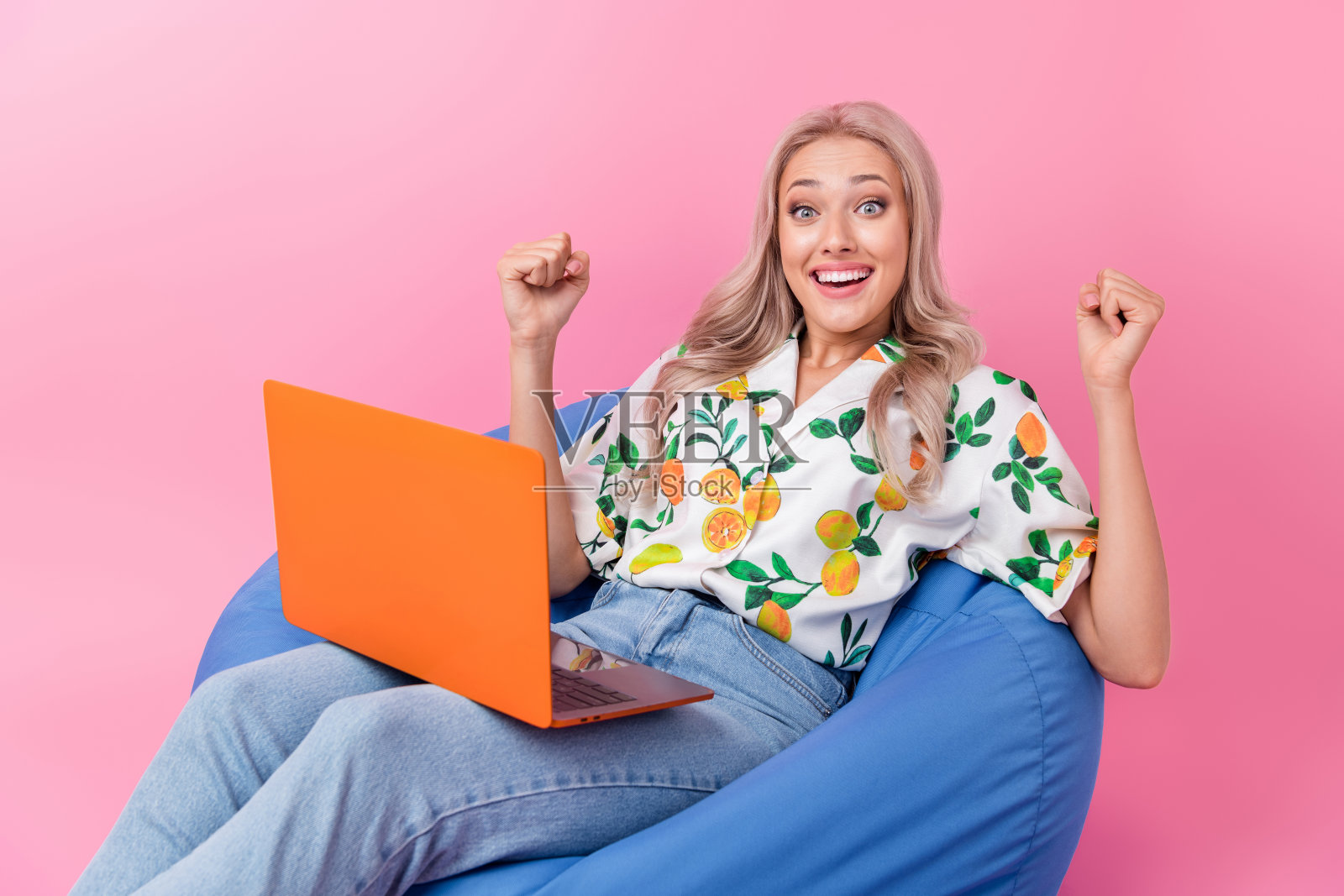 疯狂的冠军庆祝她的利润赌注在线赌场女孩的照片，她举起拳头，躺在粉红色的背景上花钱照片摄影图片