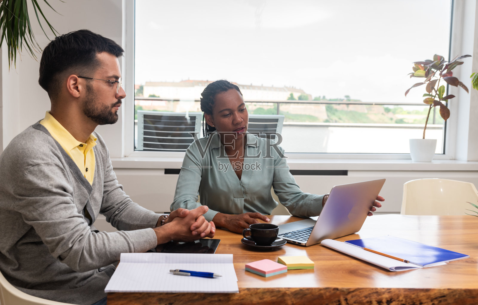 两个年轻的自由商人，在现代办公室开会、分析和咨询。商业伙伴，小公司老板，致力于新项目。头脑风暴的概念照片摄影图片