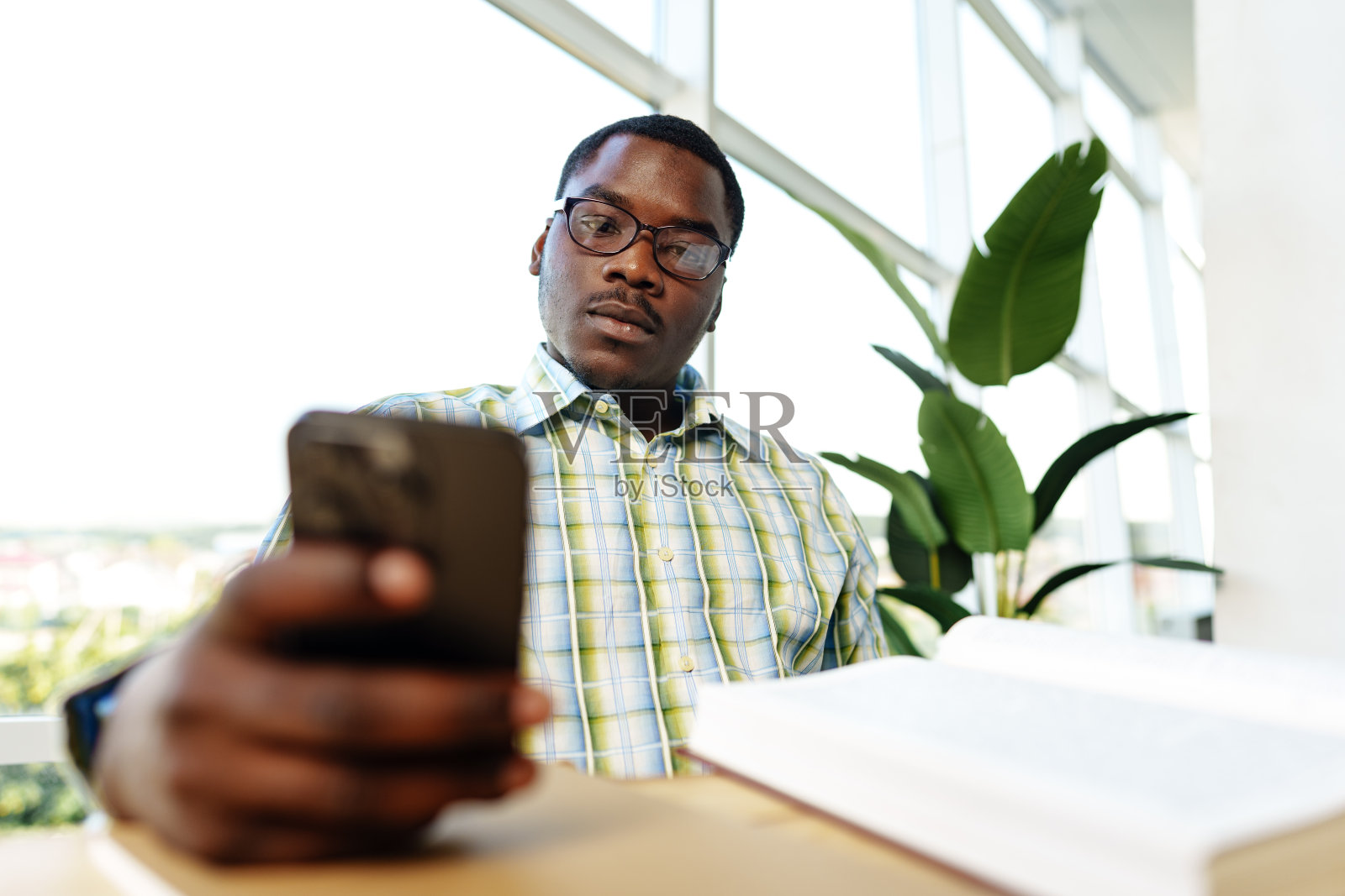 一个年轻的非洲人在办公室靠窗的地方打电话照片摄影图片