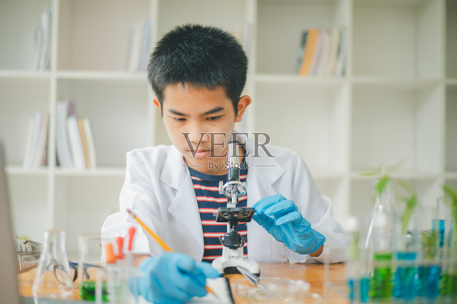 亚洲男理科学生在教室里通过显微镜观察和测试植物。学习有关植物物种的科学实验。照片摄影图片