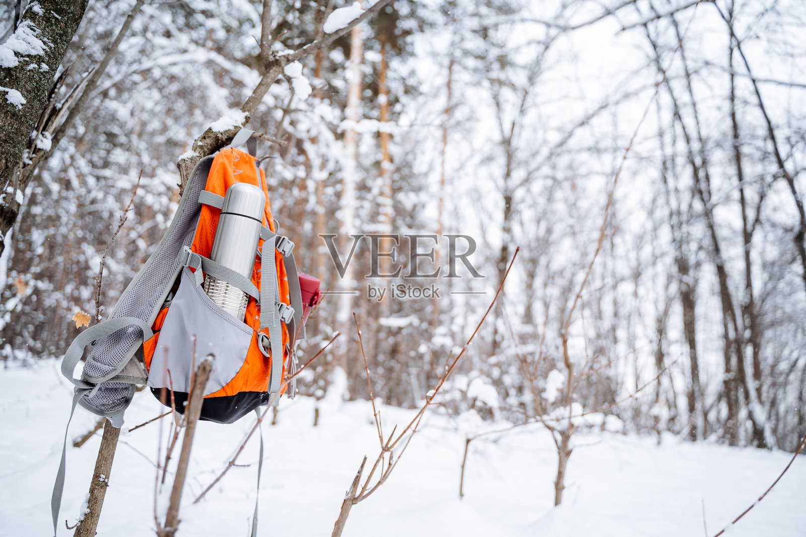 背包的外口袋里有装有茶的保温瓶。一个游客的背包挂在树上。登山用的装备。照片摄影图片