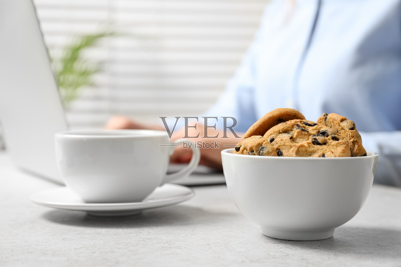 巧克力饼干和一杯饮料放在桌子上和办公室工作人员的背景，特写照片摄影图片