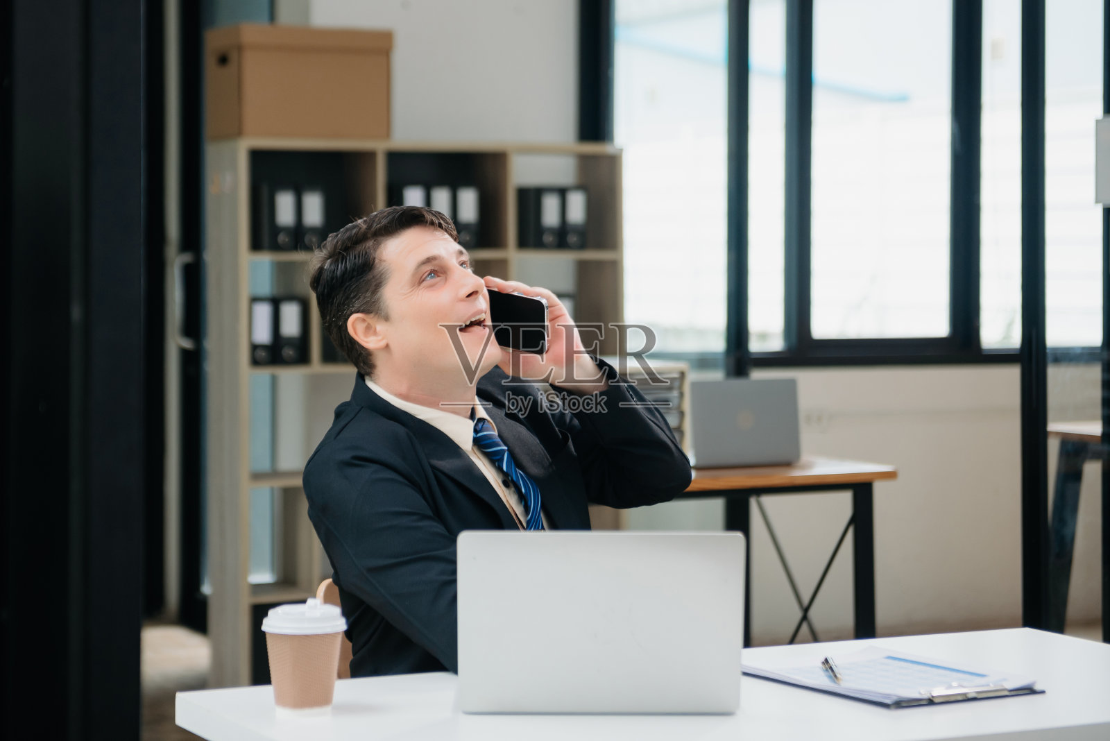 年轻的商人在办公室用笔记本电脑、平板电脑和在纸上做笔记。照片摄影图片
