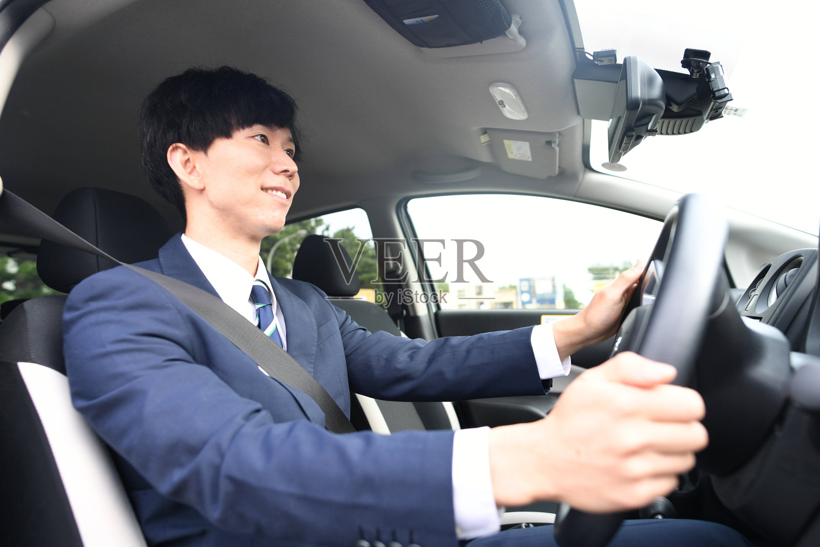 穿着西装开车的亚裔男性司机照片摄影图片