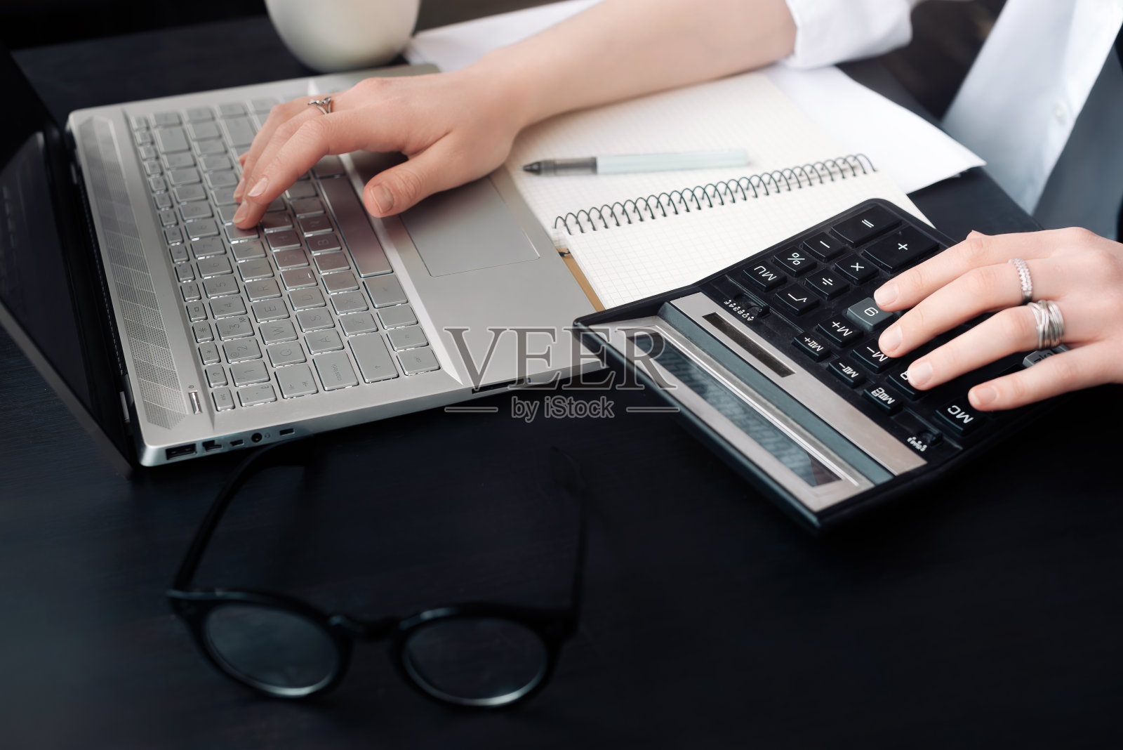 高效会计:女性在办公室使用计算器和笔记本电脑，拥抱财务和会计，即使在家工作照片摄影图片