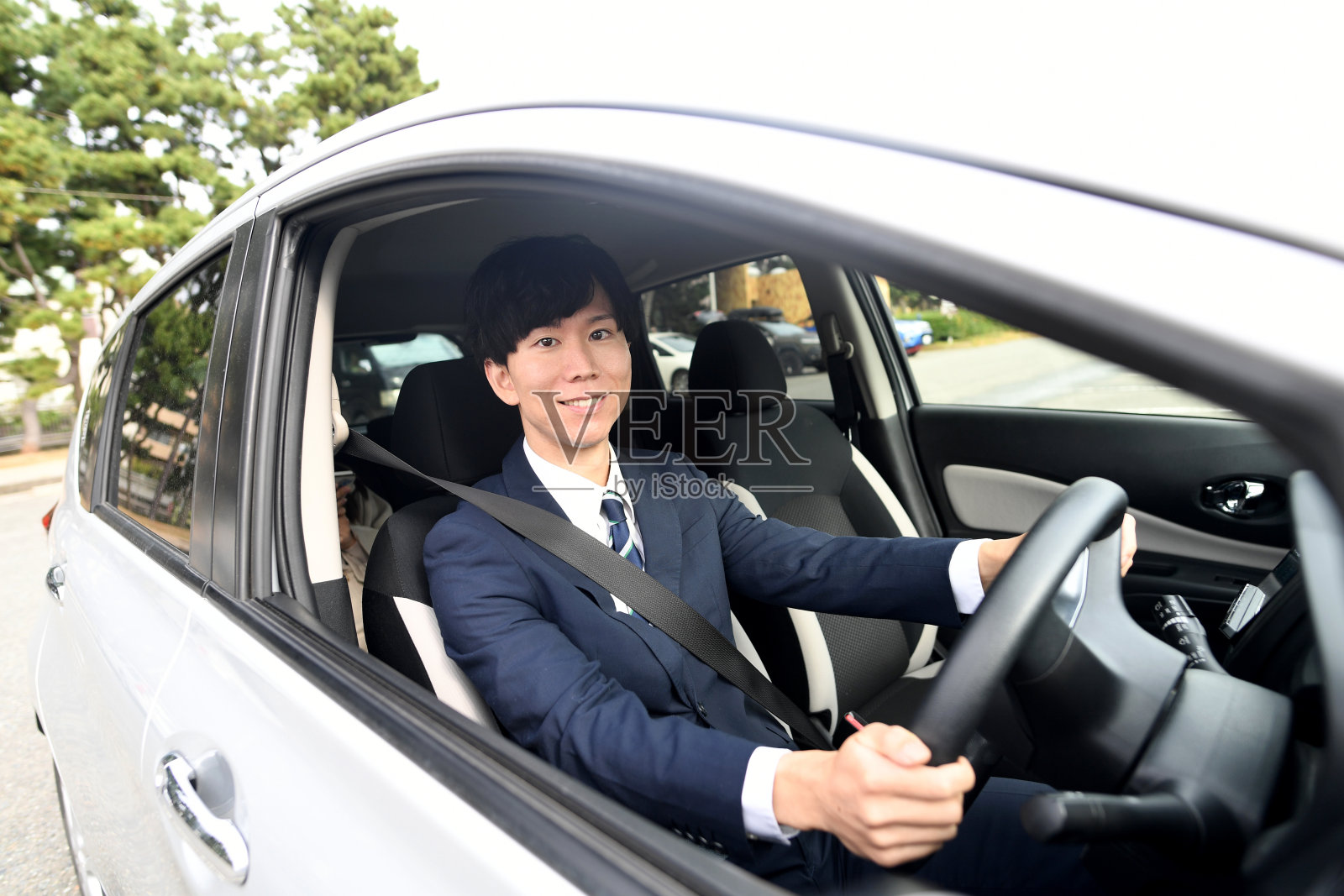 穿着西装开车的亚裔男性司机照片摄影图片
