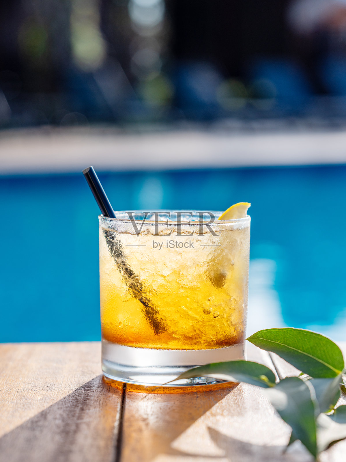 泳池前的木桌上放着柠檬酒鸡尾酒。夏日度假清凉饮料的概念照片摄影图片