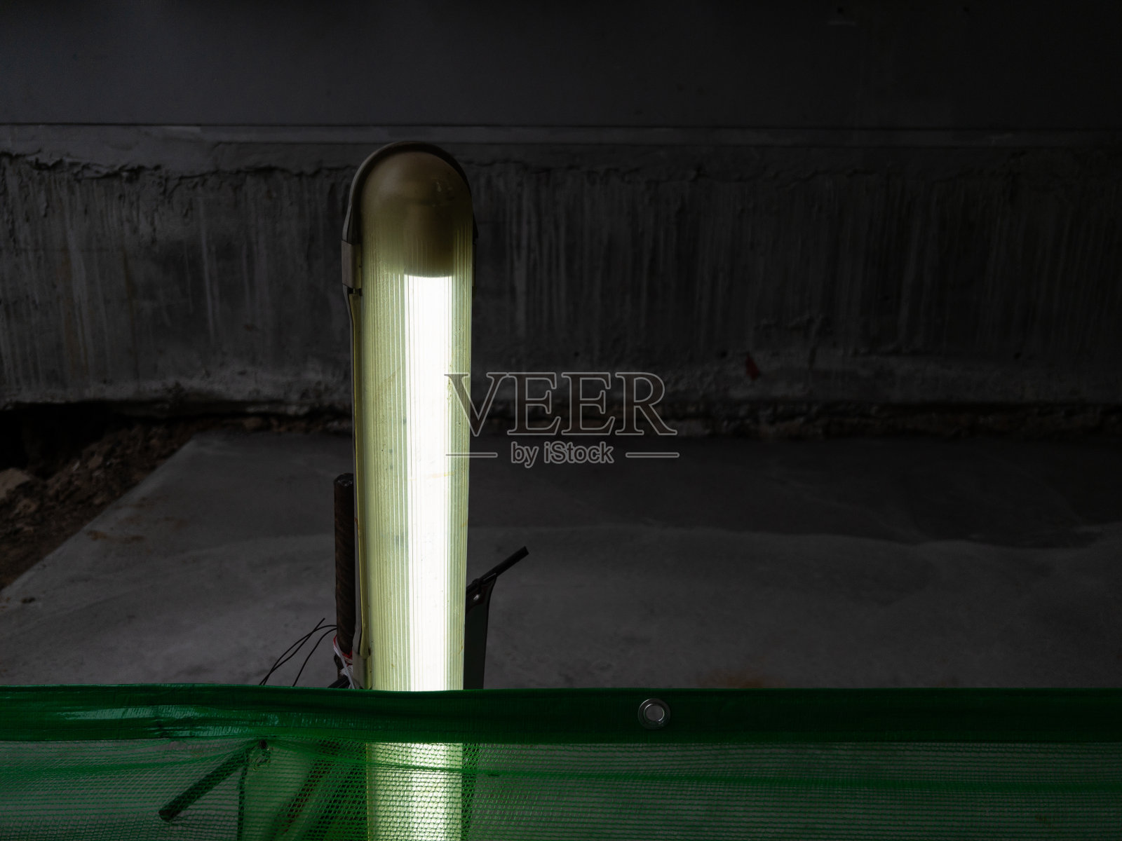 荧光灯泡挂在临时人行道的绿色缝隙上。照片摄影图片