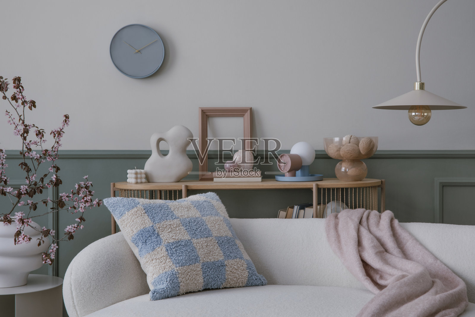 舒适的客厅内部，模拟海报框架，圆形沙发，时尚的灯，现代雕塑，花瓶与开花的树枝，图案枕头和个人配件。家居装饰。模板。照片摄影图片