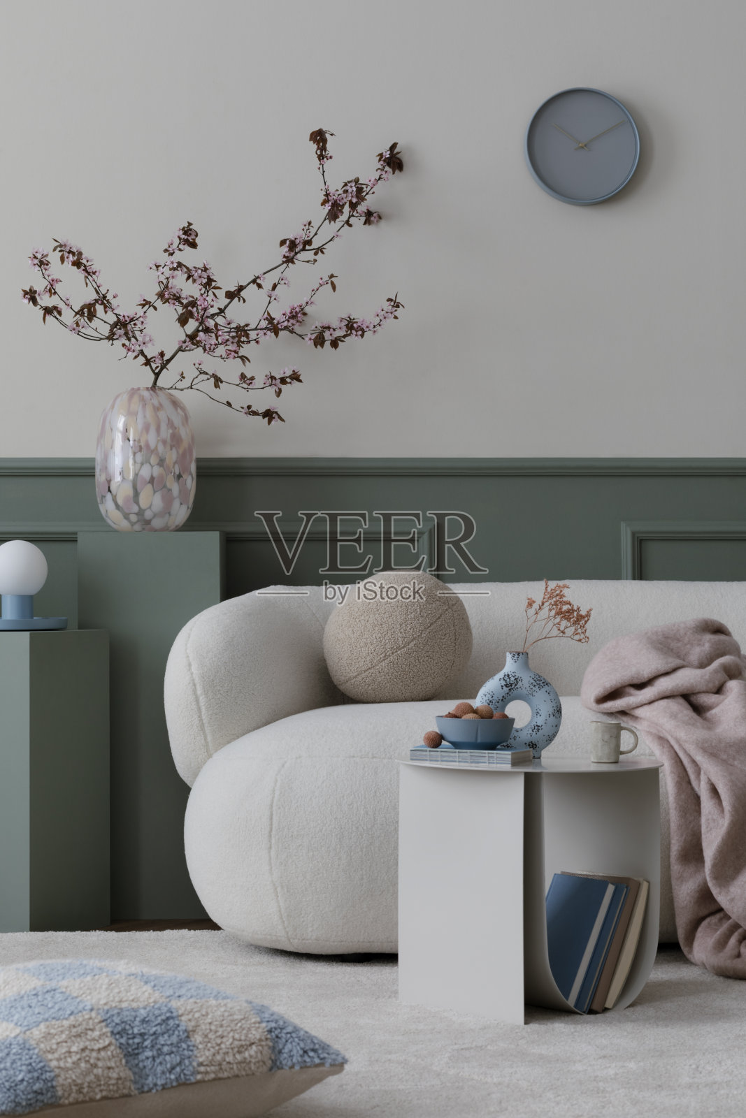 春天客厅室内的创意构图，用圆沙发，时尚的茶几，绿色的支架，带花枝的玻璃花瓶和个人饰品。家居装饰。模板。照片摄影图片