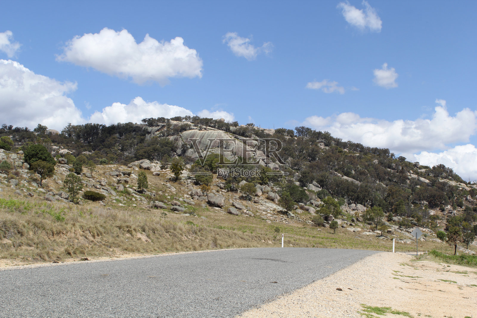 在澳大利亚新南威尔士州滕特菲尔德附近的麦肯齐山旅游大道上，花岗岩山露出地面，有道路、草地和树木照片摄影图片