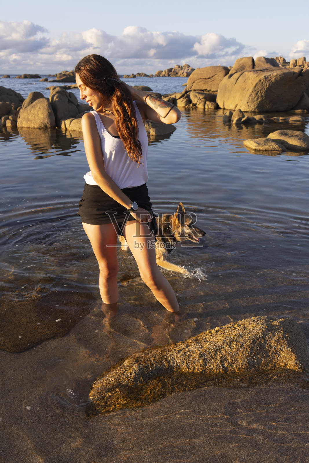 年轻的拉丁女人在沙滩上和狗玩耍照片摄影图片