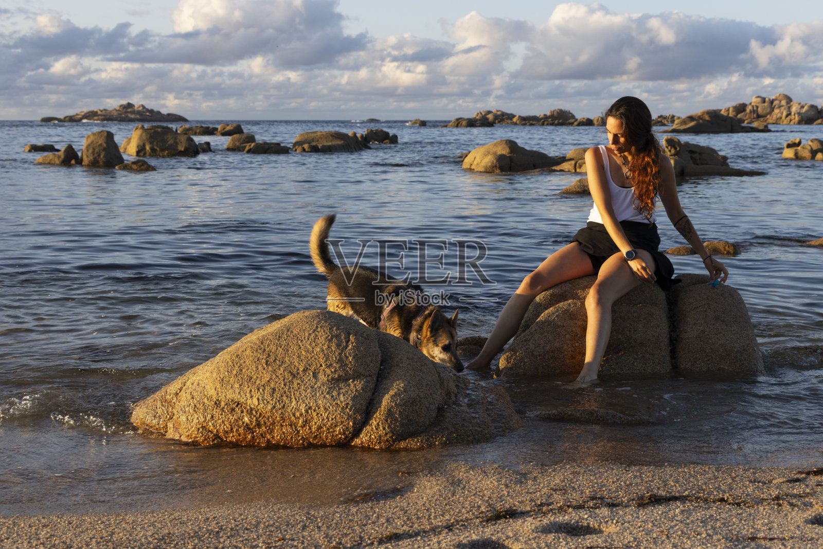 年轻女子坐在大海的岩石上照片摄影图片