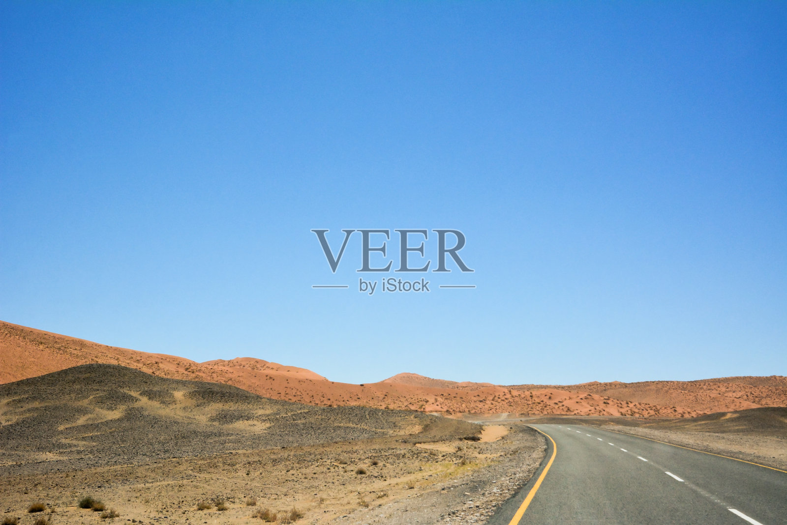 沥青路的视角，背景是遥远的沙漠山丘照片摄影图片