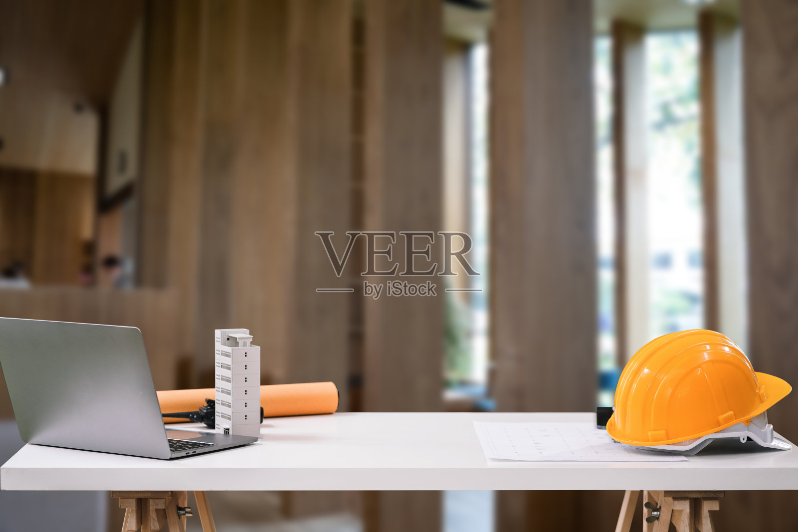 建造房屋和建筑物。修复工作。办公室桌子上的笔记本电脑和办公室建筑模糊的背景。建筑师的概念。照片摄影图片