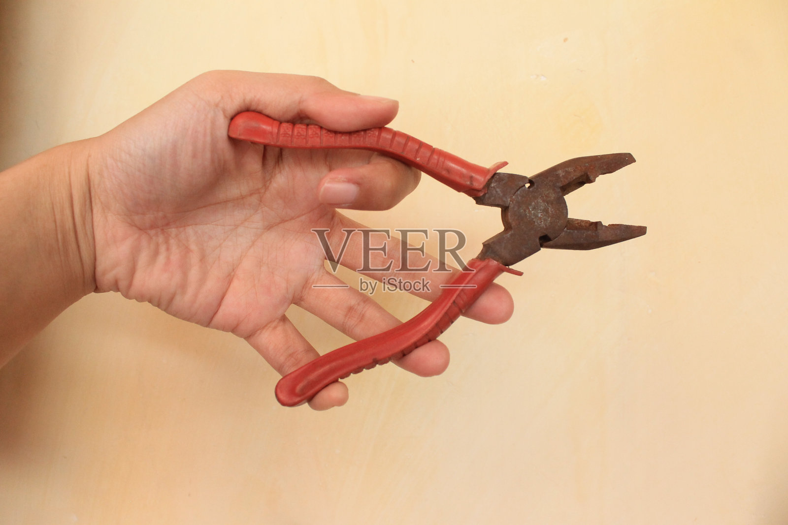 近距离的手拿着一个红色生锈的钳子在黄色的背景照片摄影图片