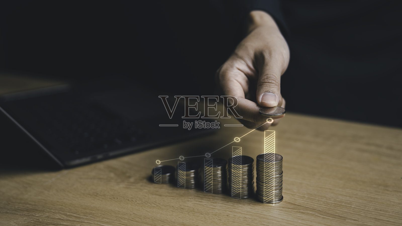 一个商人拿着一堆硬币进行金融增长和投资。硬币排列成一个稳步上升的条形图。预算管理与利润。照片摄影图片