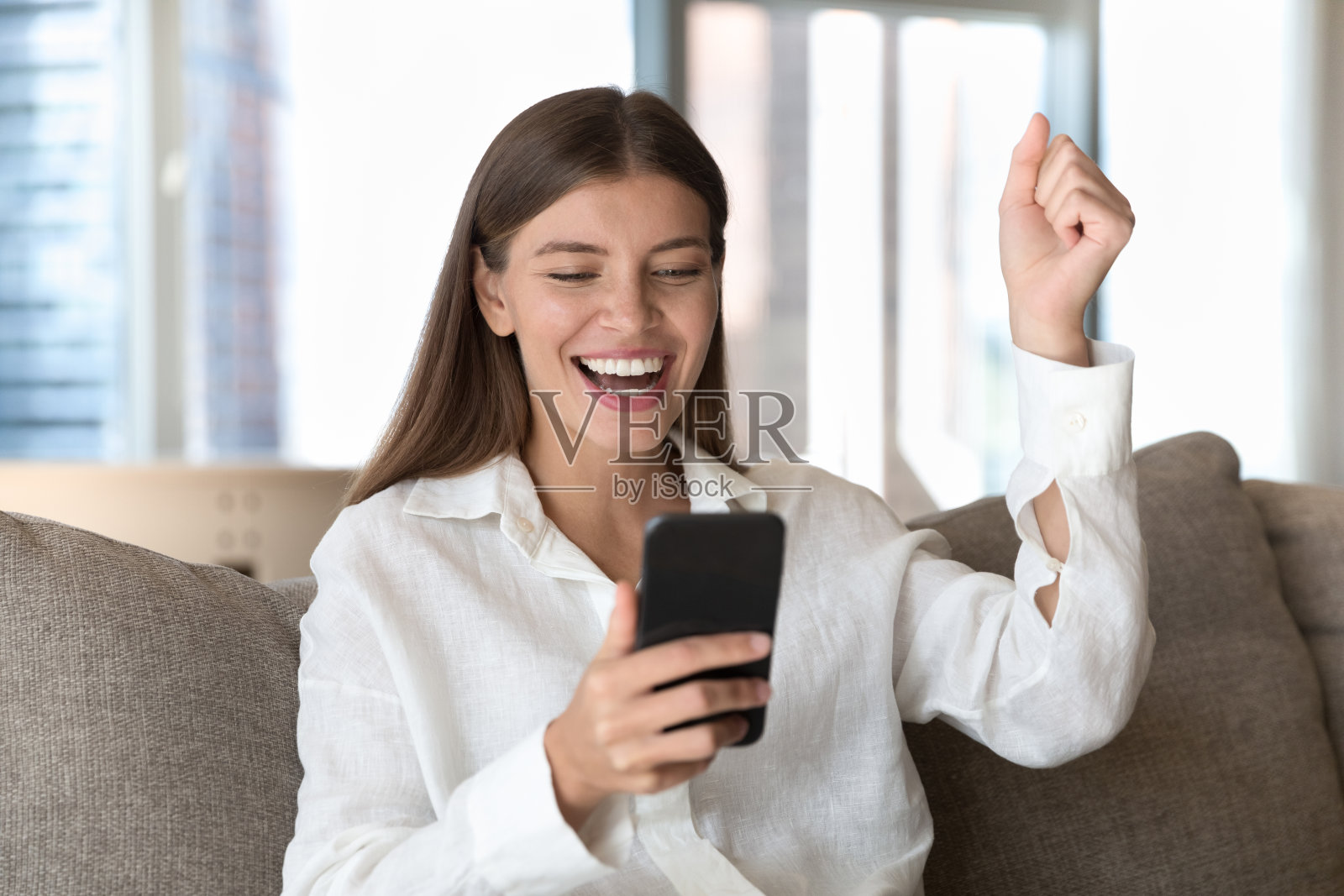 女人看着手机屏幕读到好消息感到高兴照片摄影图片