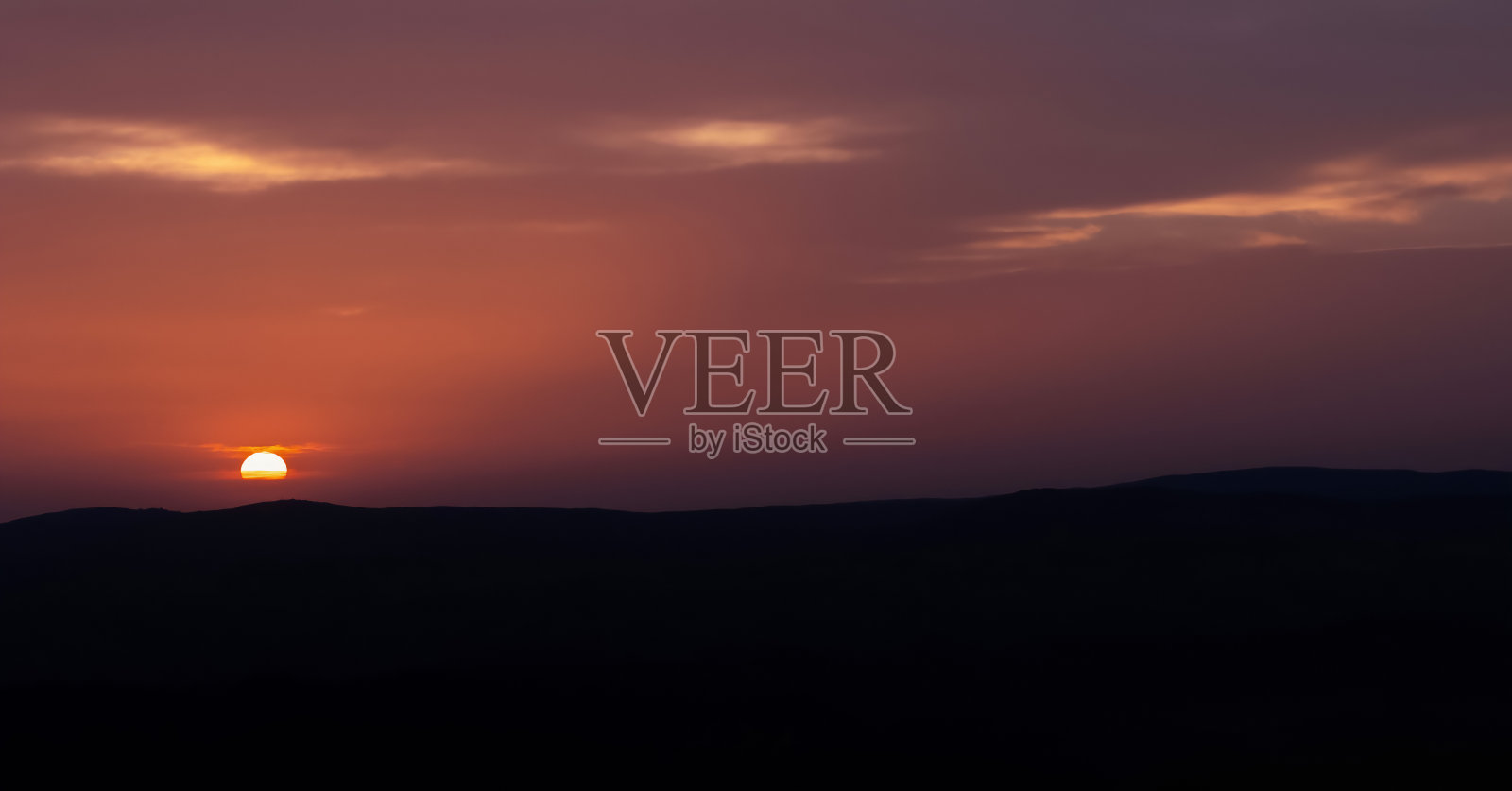 晚霞苍穹景观配山峦剪影，美丽的太阳悬在云中照片摄影图片