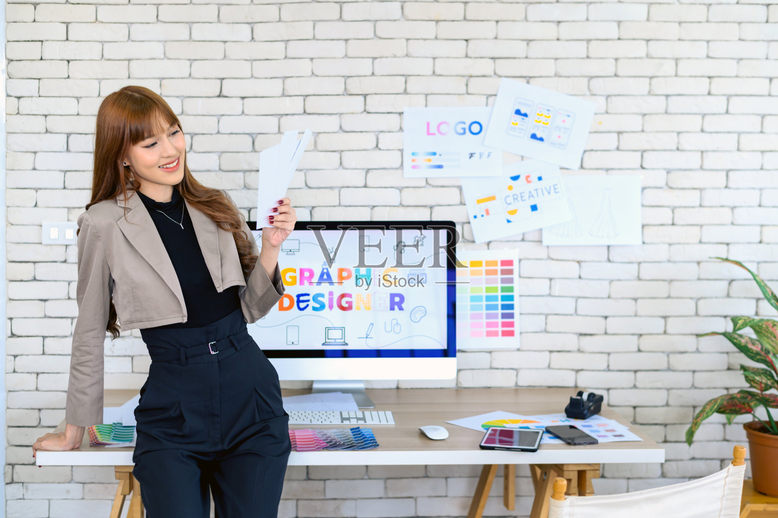 年轻的亚洲女性图形设计师，在办公室工作与图表，颜色和电脑图形。照片摄影图片