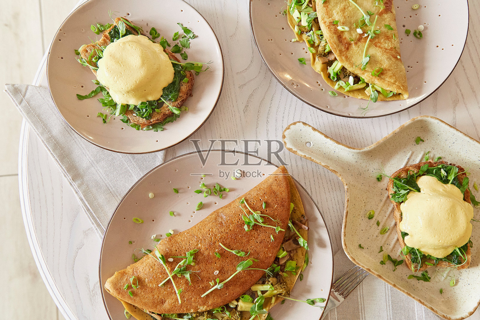 素食煎饼配蘑菇，豌豆芽，鳄梨。本尼迪克特鸡蛋配植物酱，酸面包，豆腐，嫩洋葱，青菜。健康的早餐。俯视图食物照片摄影图片
