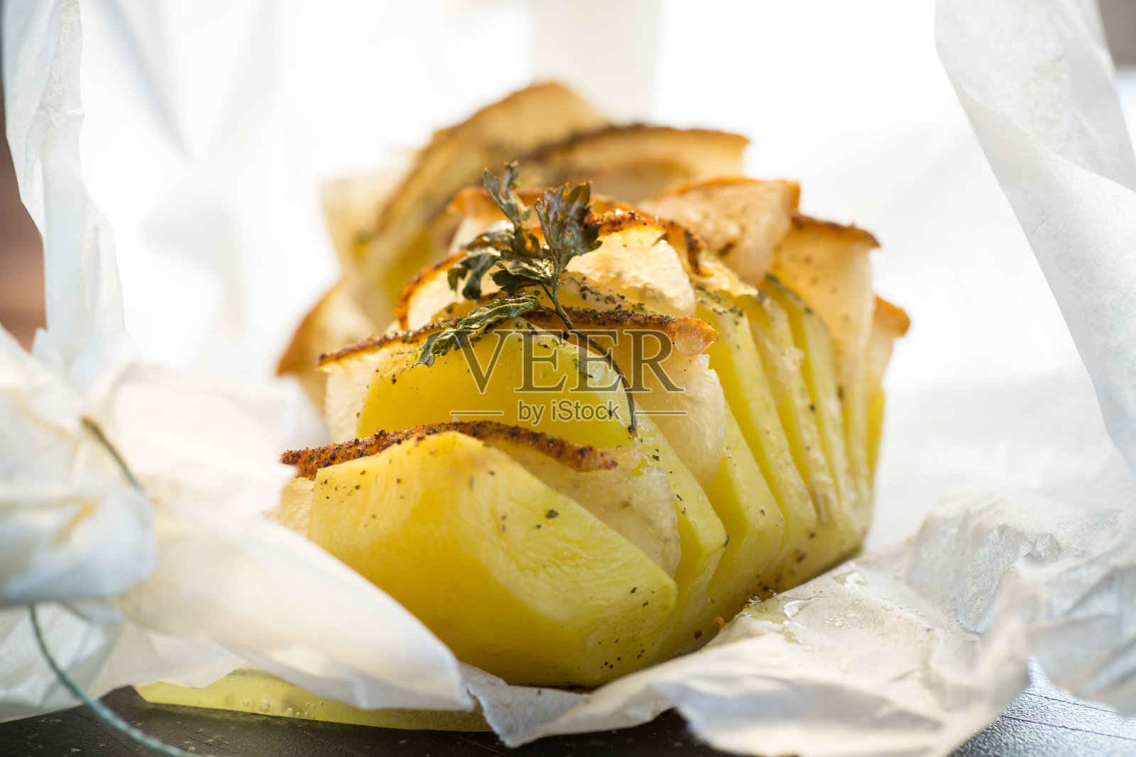 在烤纸里塞满猪油的烤土豆。照片摄影图片