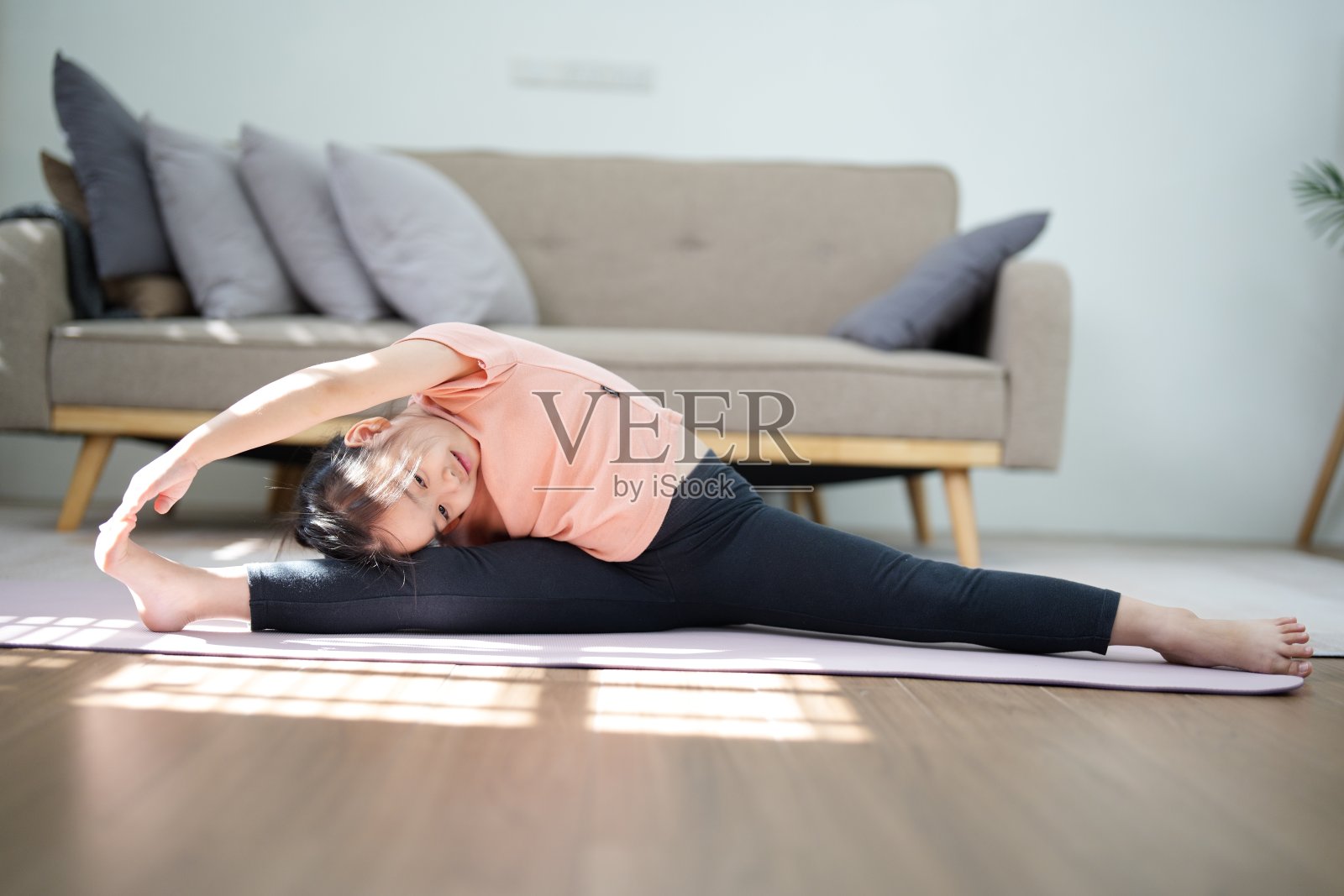 可爱的小女孩在客厅里劈腿，健康的居家生活理念照片摄影图片