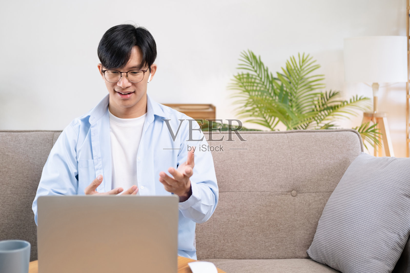 一个戴着耳机在笔记本电脑上远程办公的年轻人正在开会。照片摄影图片