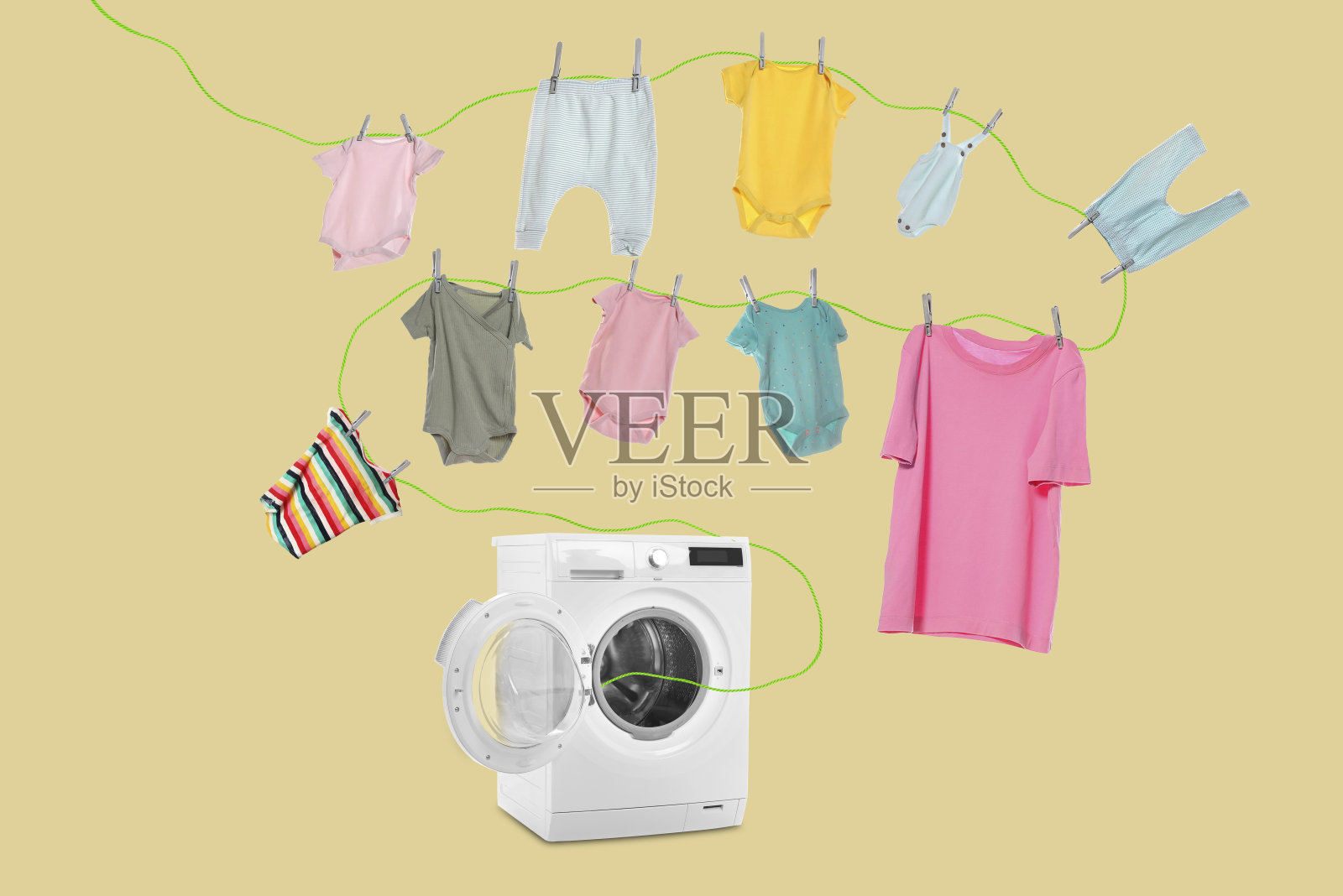 干燥的衣服。米色背景上，绳子上挂着从洗衣机里飞出来的童装照片摄影图片