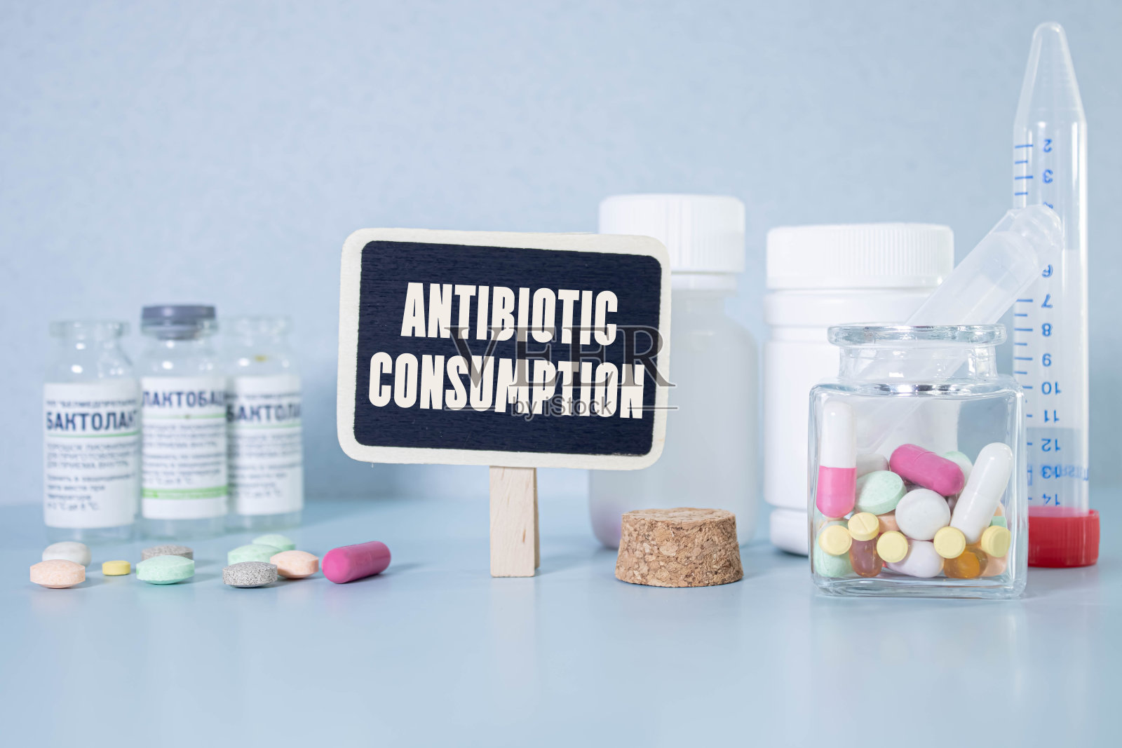 桌子上放着一个带纸的剪贴板，旁边是药品和注射器。铭文抗生素消费。医学概念。照片摄影图片