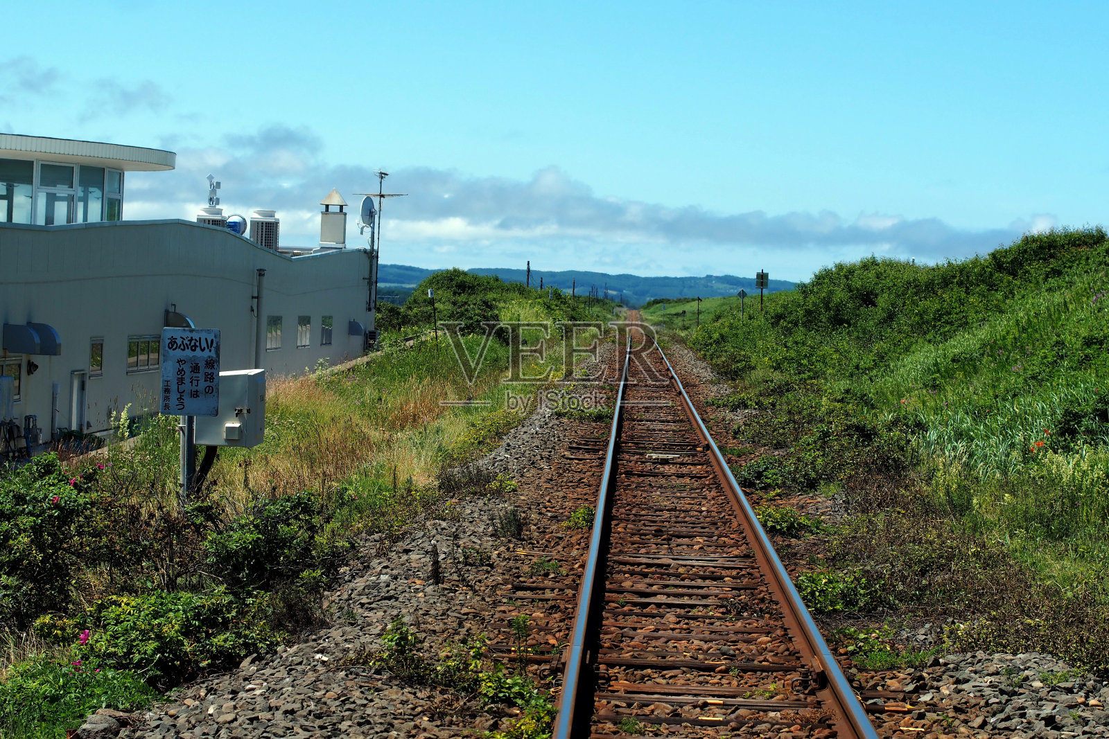 日本农村铁路的图片。铁路一望无际。背景是群山和蓝天。照片摄影图片