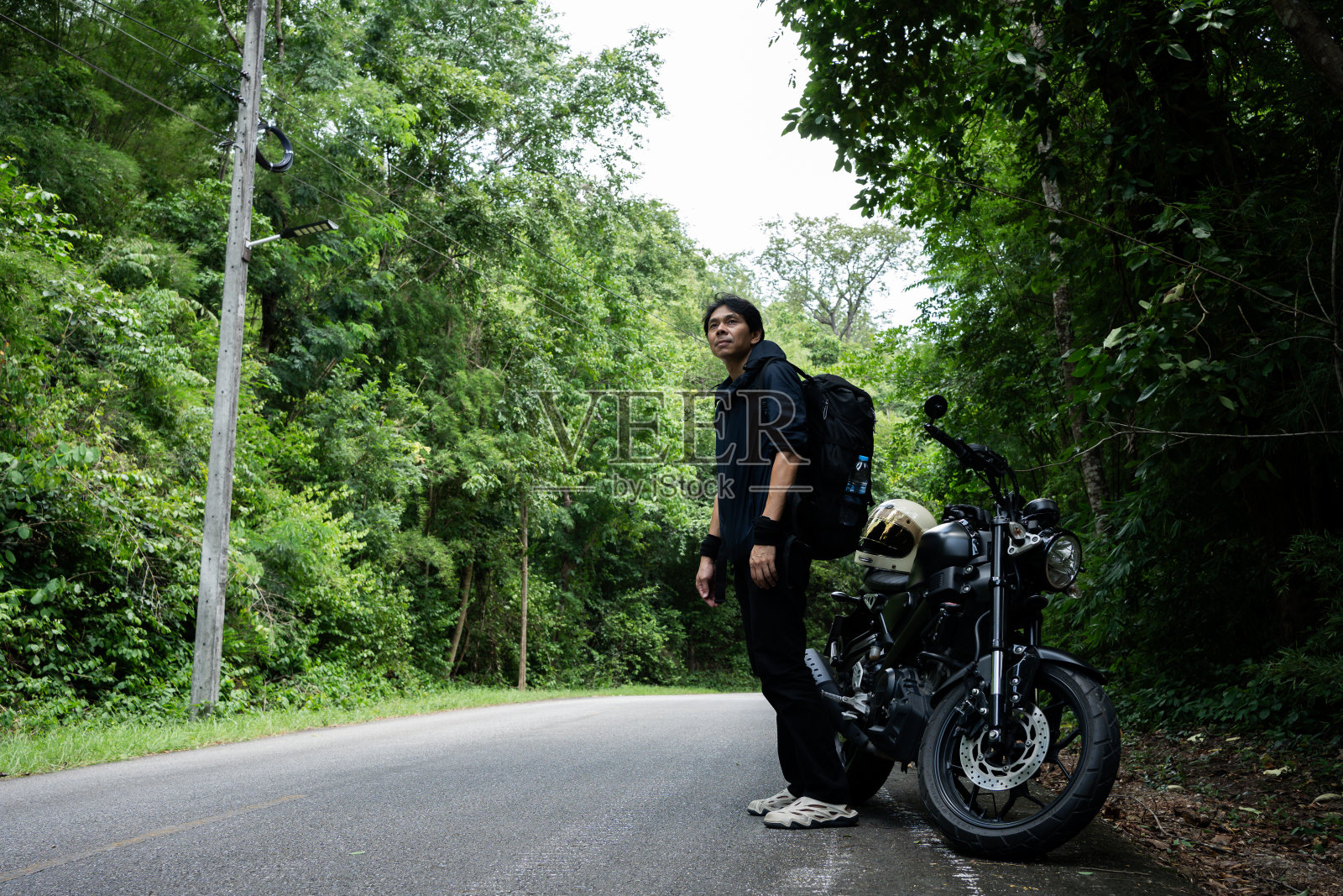 人们的活动理念是亚洲男子骑摩托车在热带森林里拍照照片摄影图片