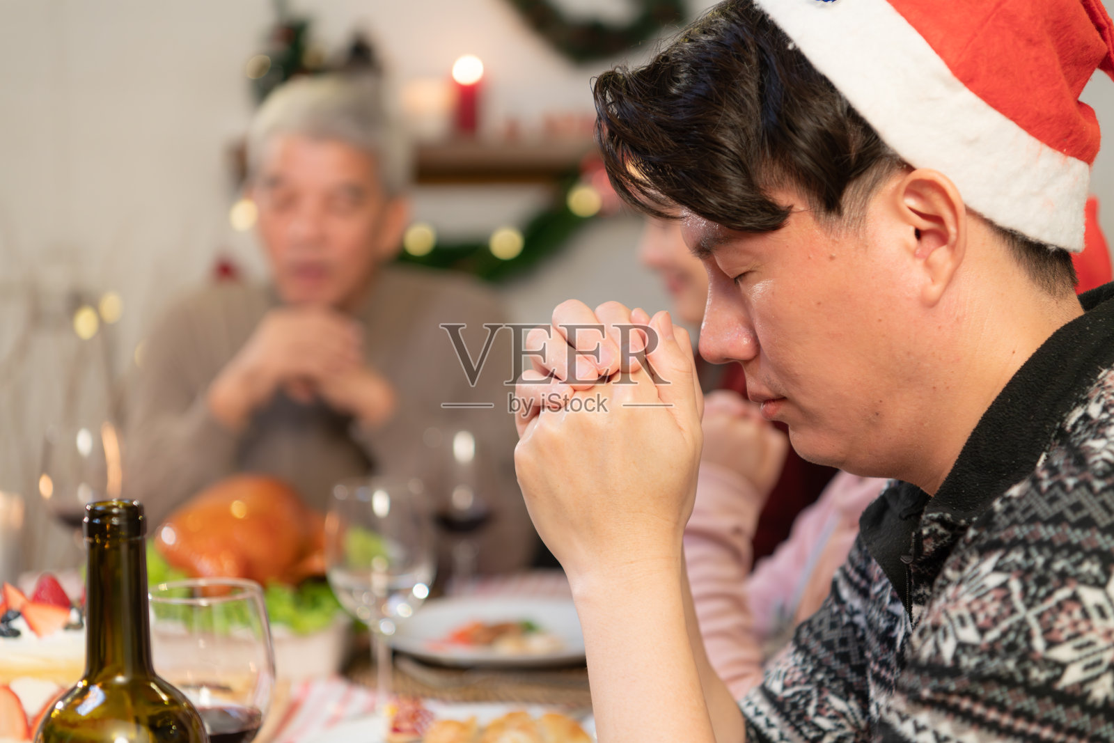 年轻的亚洲男子和家人在家里的圣诞晚餐上祈祷照片摄影图片