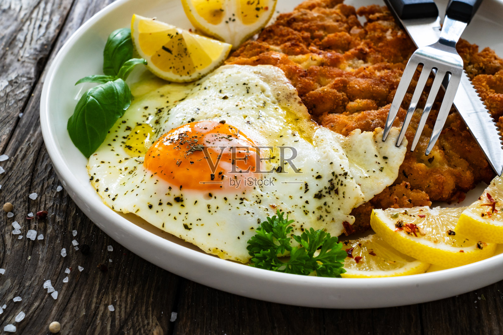 木桌上脆脆的面包屑烤鸡排配上煎蛋和柠檬照片摄影图片