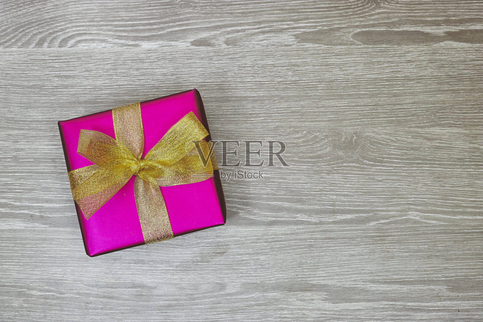 粉红色的礼品盒与金色丝带在灰色的木材背景照片摄影图片