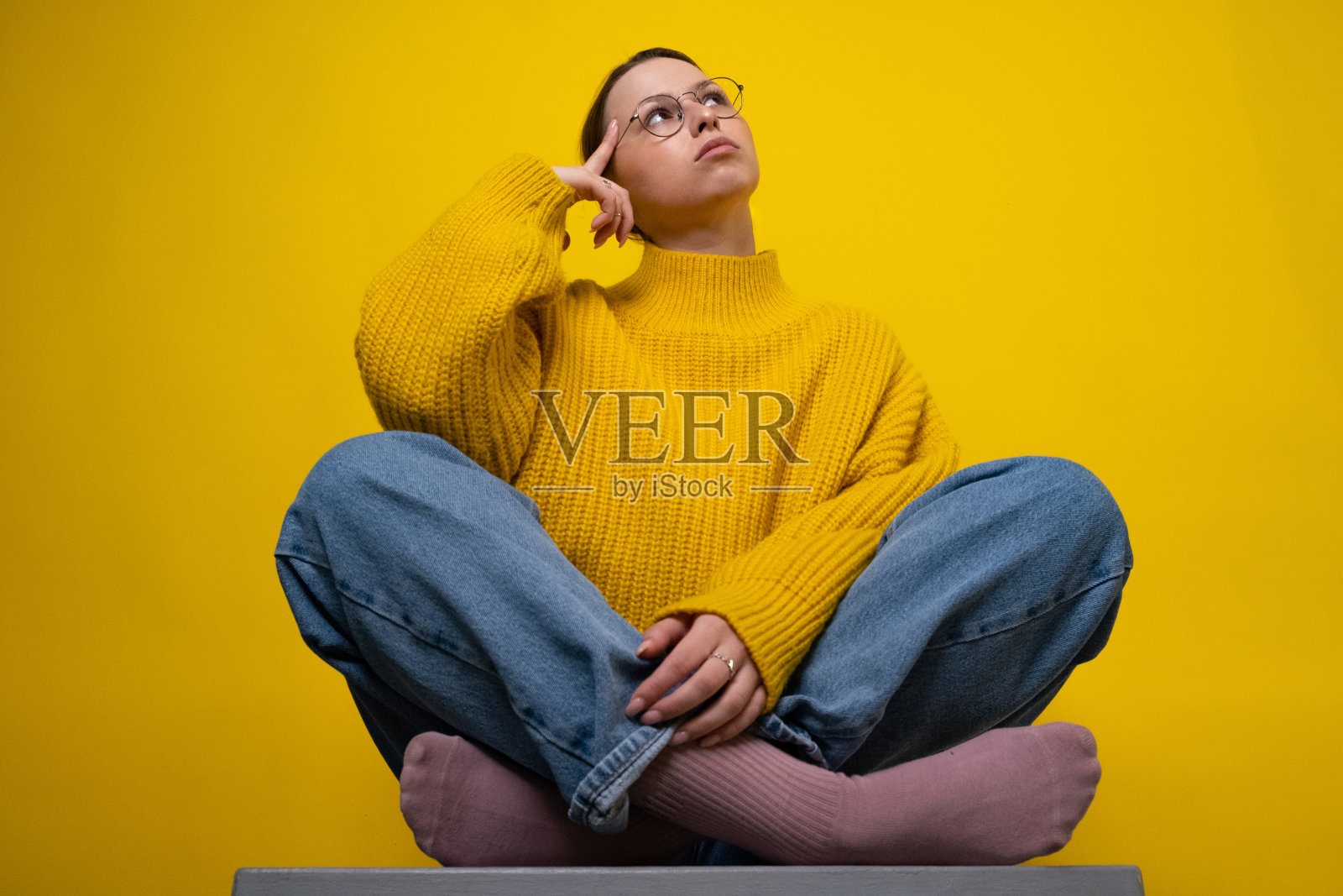 创意女性的肖像，手臂触摸下巴，看起来空的空间头脑风暴孤立在黄色背景照片摄影图片