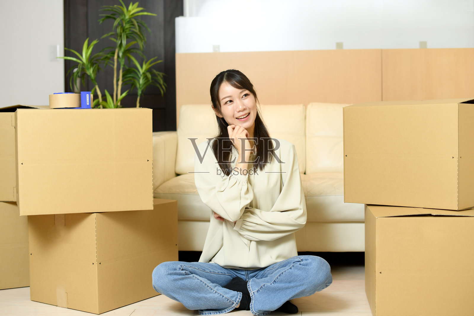 一个亚洲年轻女子在纸板箱前微笑着思考照片摄影图片