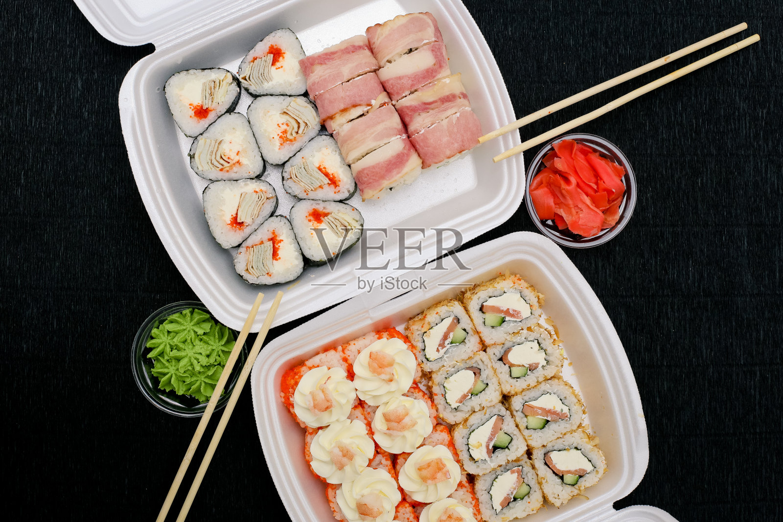 一套寿司和卷装在一个黑色背景的塑料盒里照片摄影图片