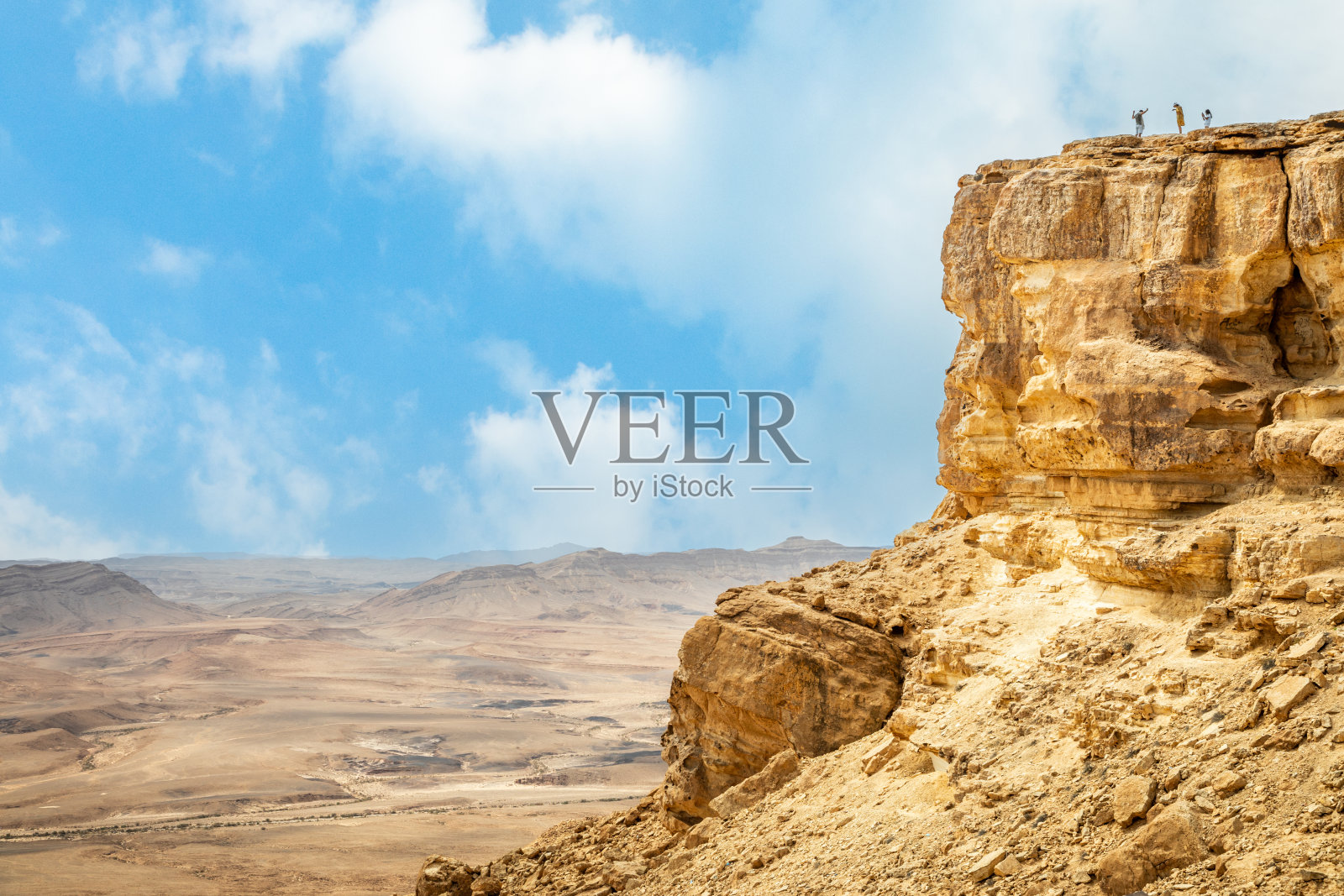 内盖夫沙漠 erosion 陨石坑地貌全景，以色列 Makhtesh Ramon 岩石顶部的小人照片摄影图片