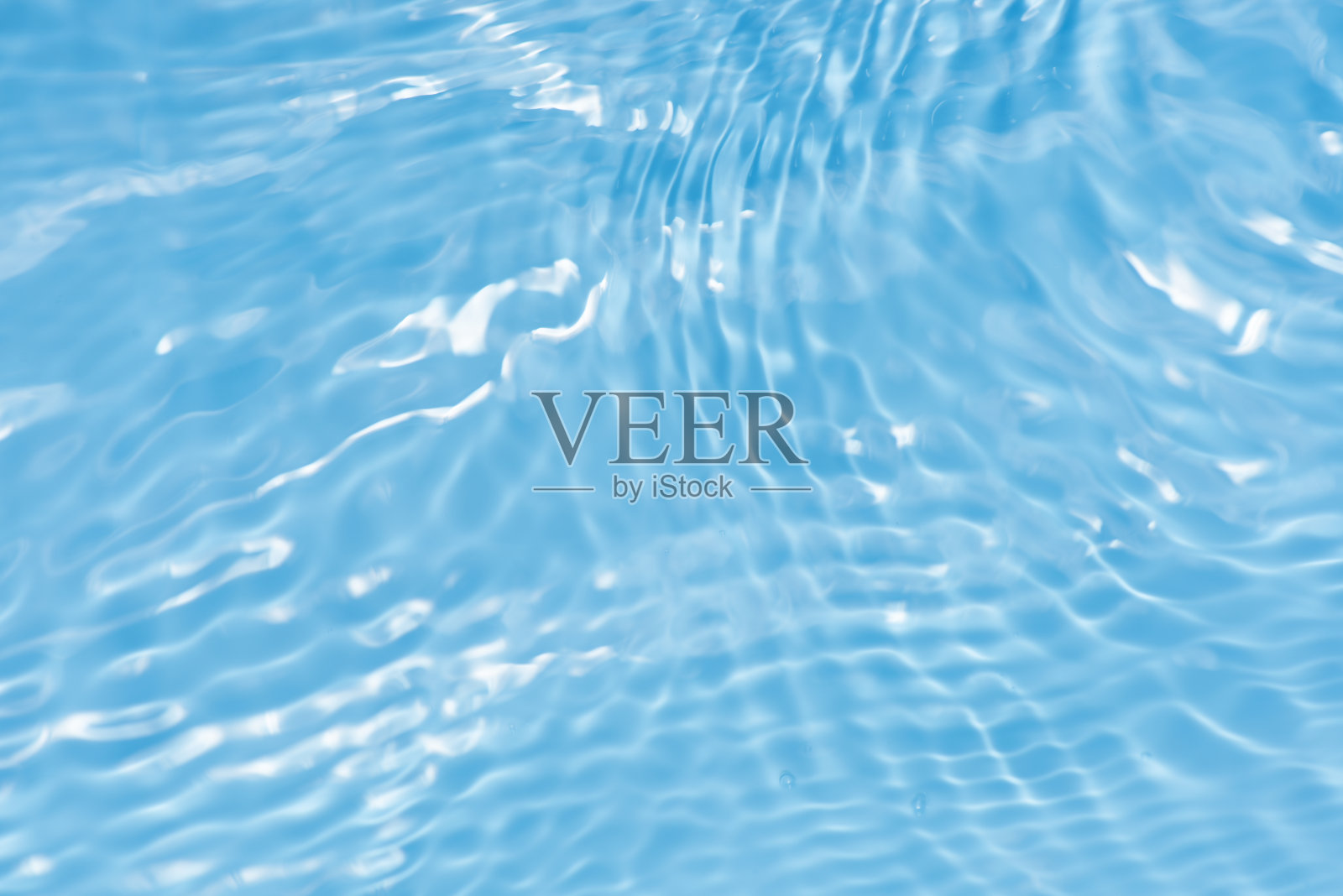 散焦模糊透明蓝色透明平静水面纹理与飞溅反射。新潮抽象的自然背景。水波在阳光下与复制空间。蓝色水彩光泽。照片摄影图片