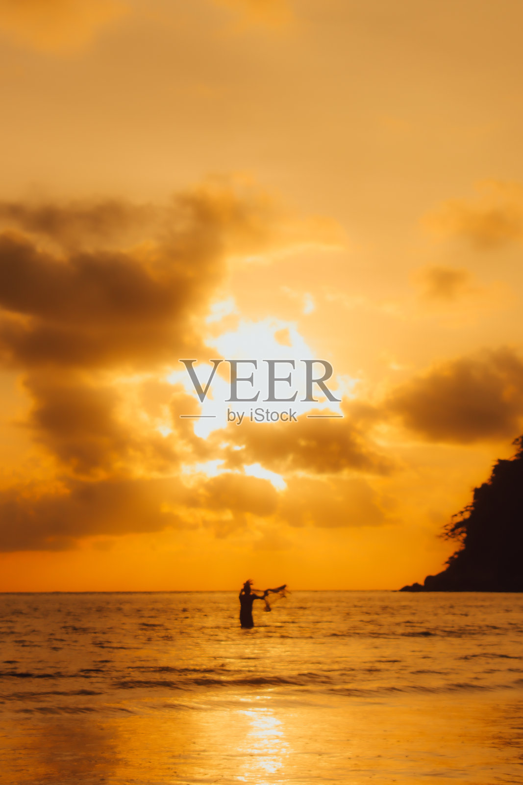 泰国普吉岛拉延海滩，夕阳西下，亚洲人在海边种鱼。照片摄影图片