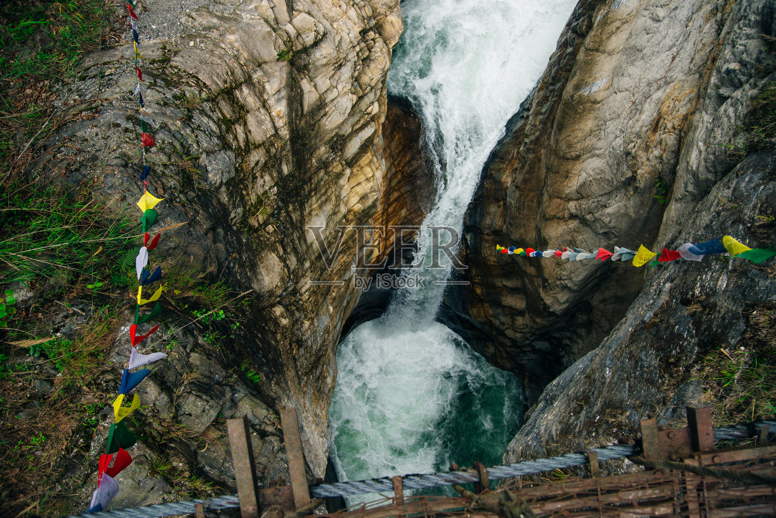 尼泊尔喜马拉雅山上悬挂佛教经幡的吊桥。照片摄影图片