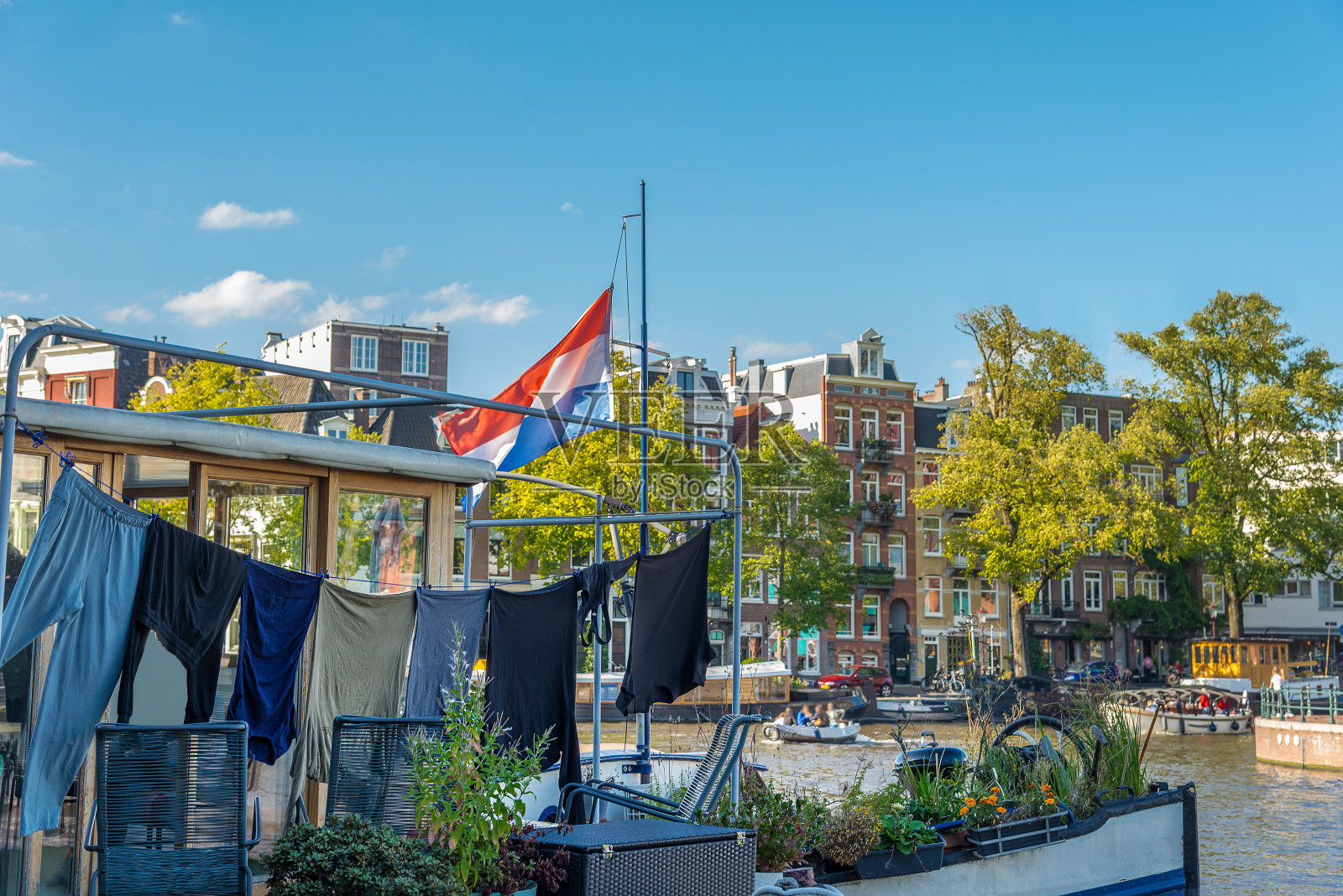 阿姆斯特丹运河上的船屋，挂着洗过的衣服和荷兰国旗。照片摄影图片