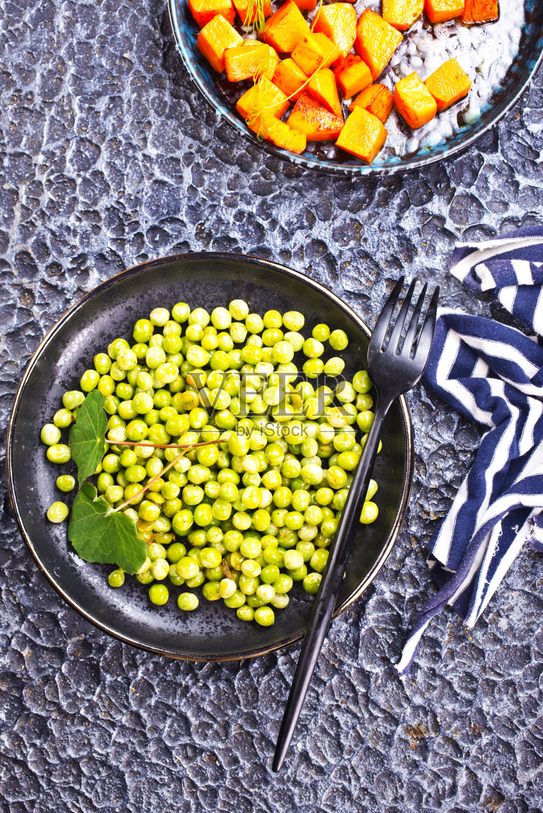 黑色沙拉碗里的豌豆和胡萝卜照片摄影图片