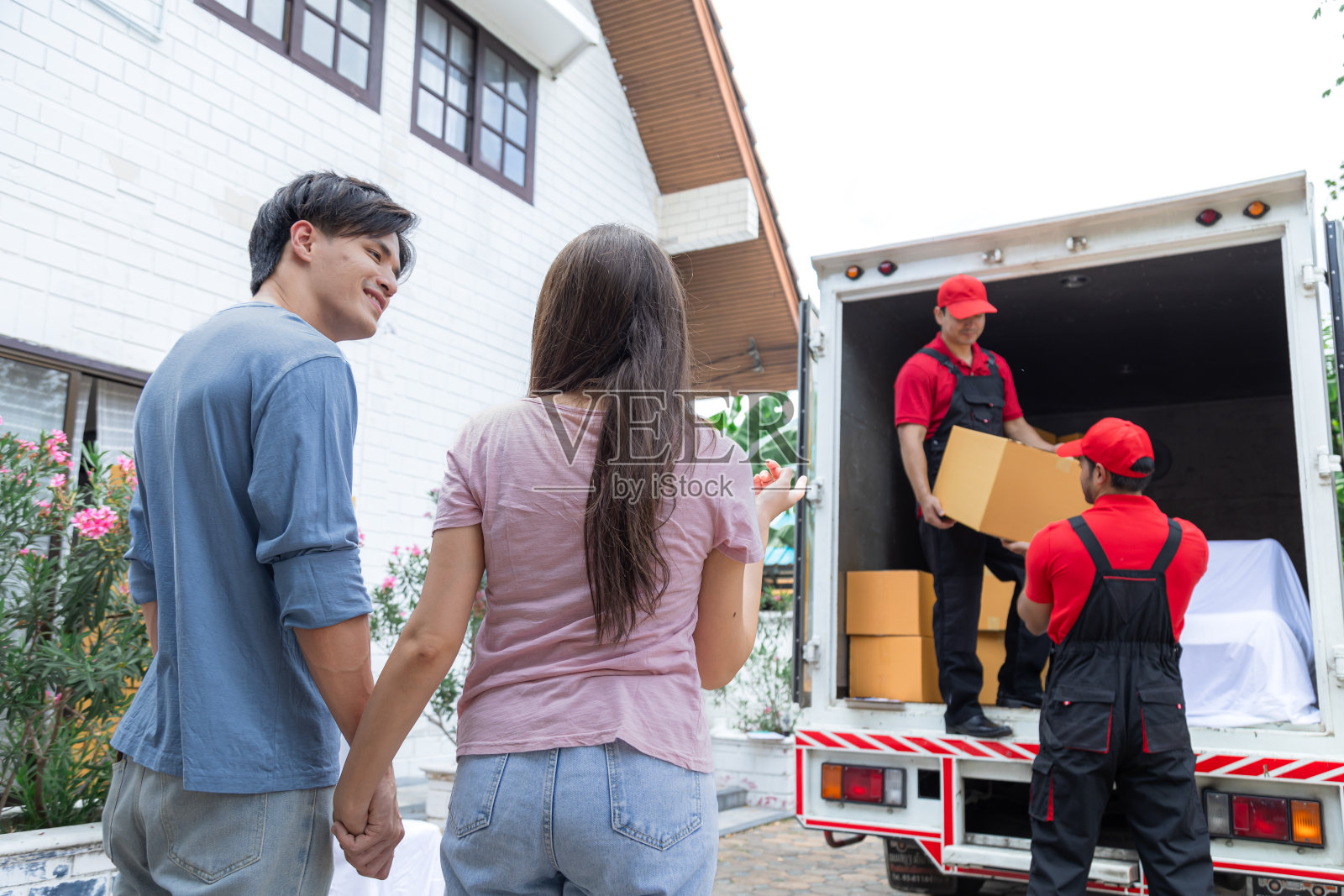 亚洲新人搬入新房采用专业的送货物流搬家业务服务，多民族印度人和白种人团队员工工作上传吊装纸箱照片摄影图片