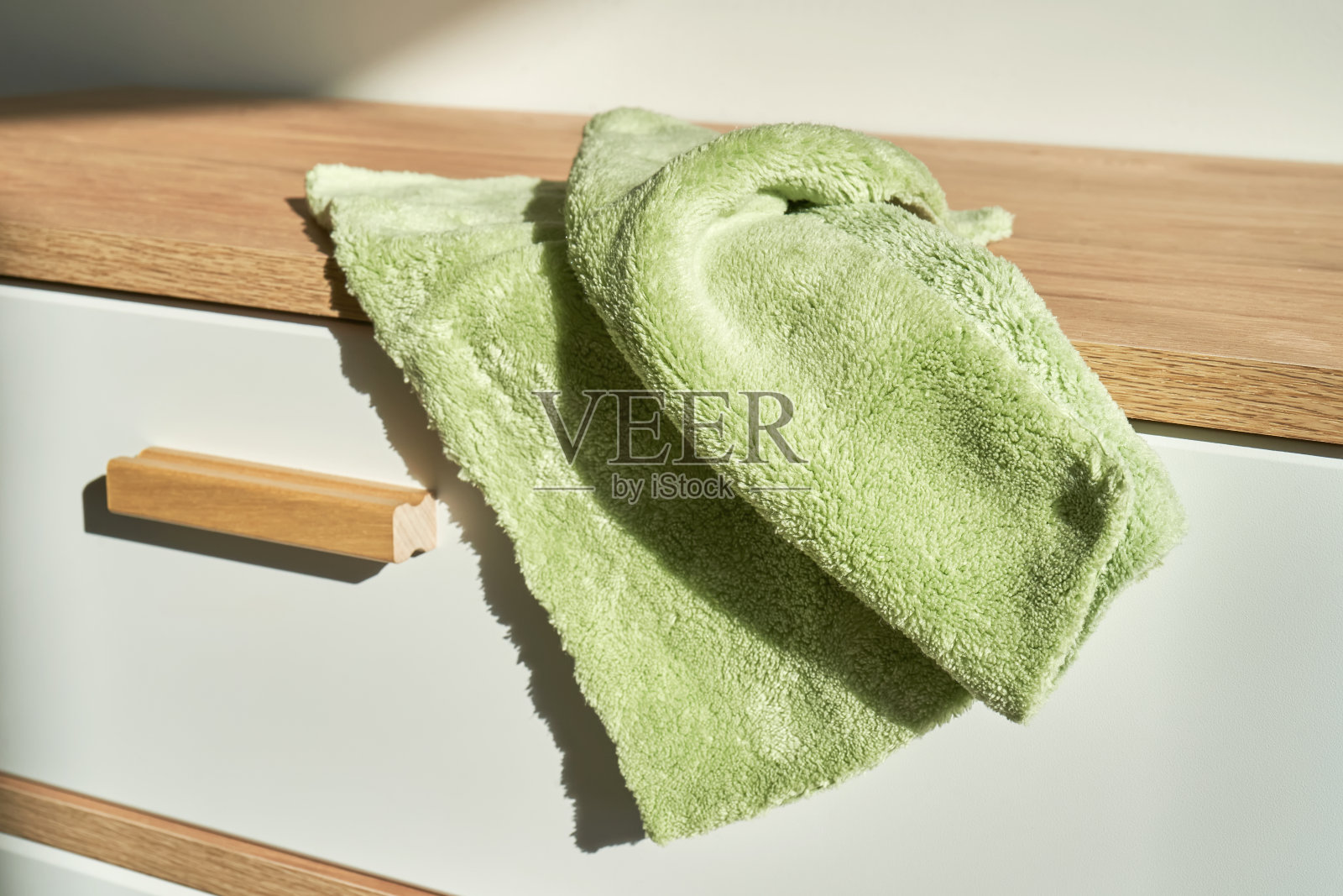 柔软的绿色长毛绒清洁布在一个白色的梳妆台在家庭环境。照片摄影图片