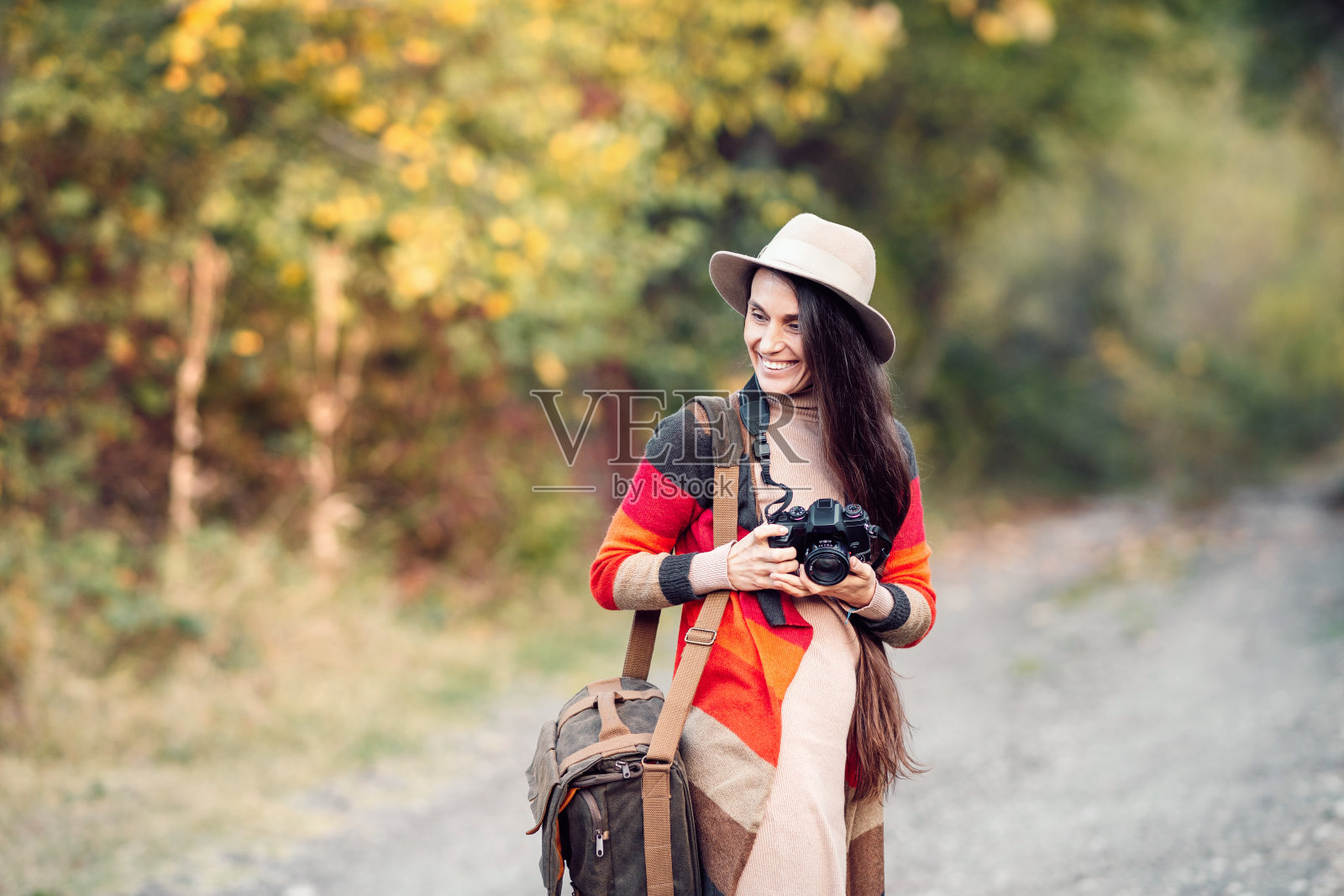 女摄影师在秋天的森林里拍照。照片摄影图片