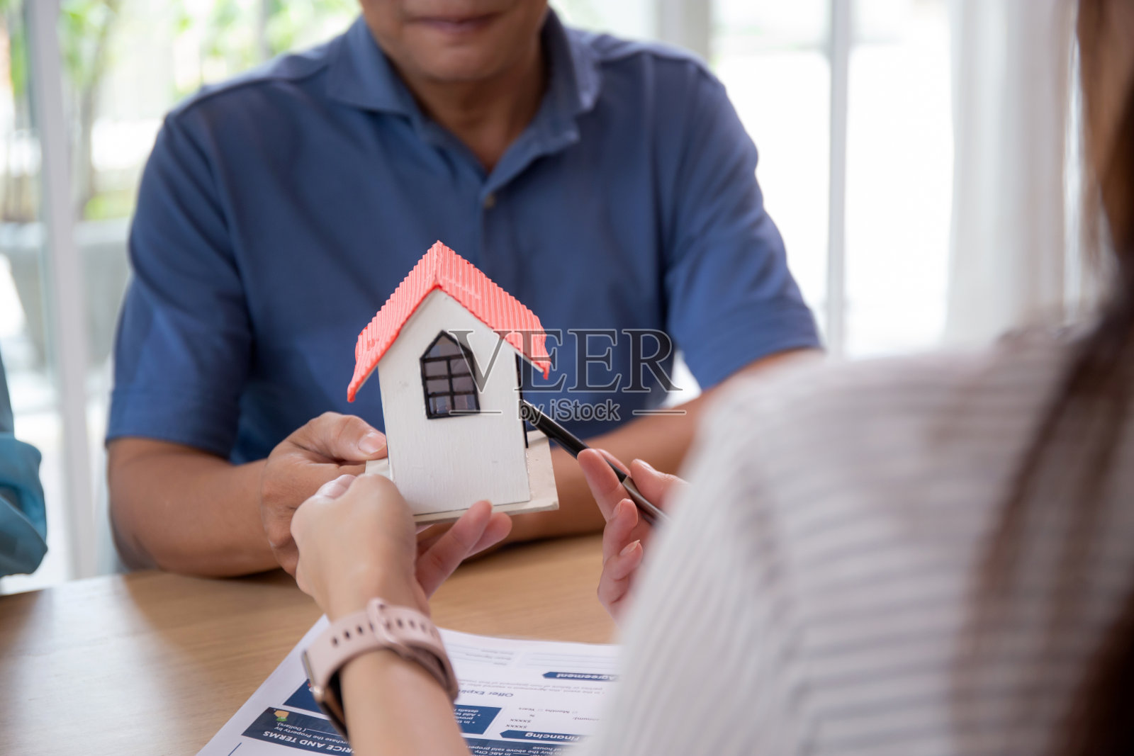 年轻的房地产女经纪人在家庭办公协议和合同达成和批准的同时向客户提供房屋模型，投资和抵押，商业和金融概念。照片摄影图片