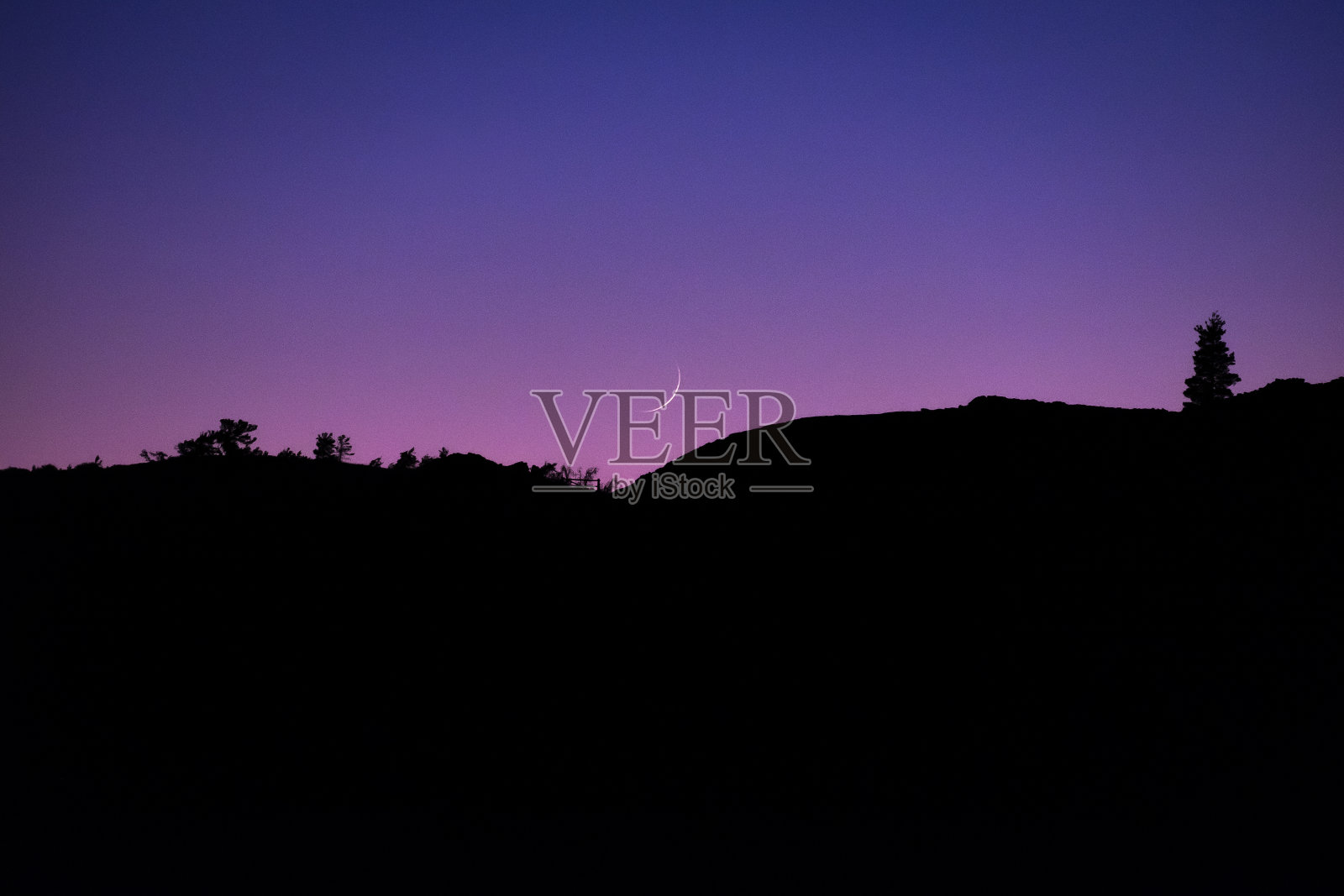 在美国爱达荷州的月球环形山上，一轮新月降落在紫色的天空中照片摄影图片